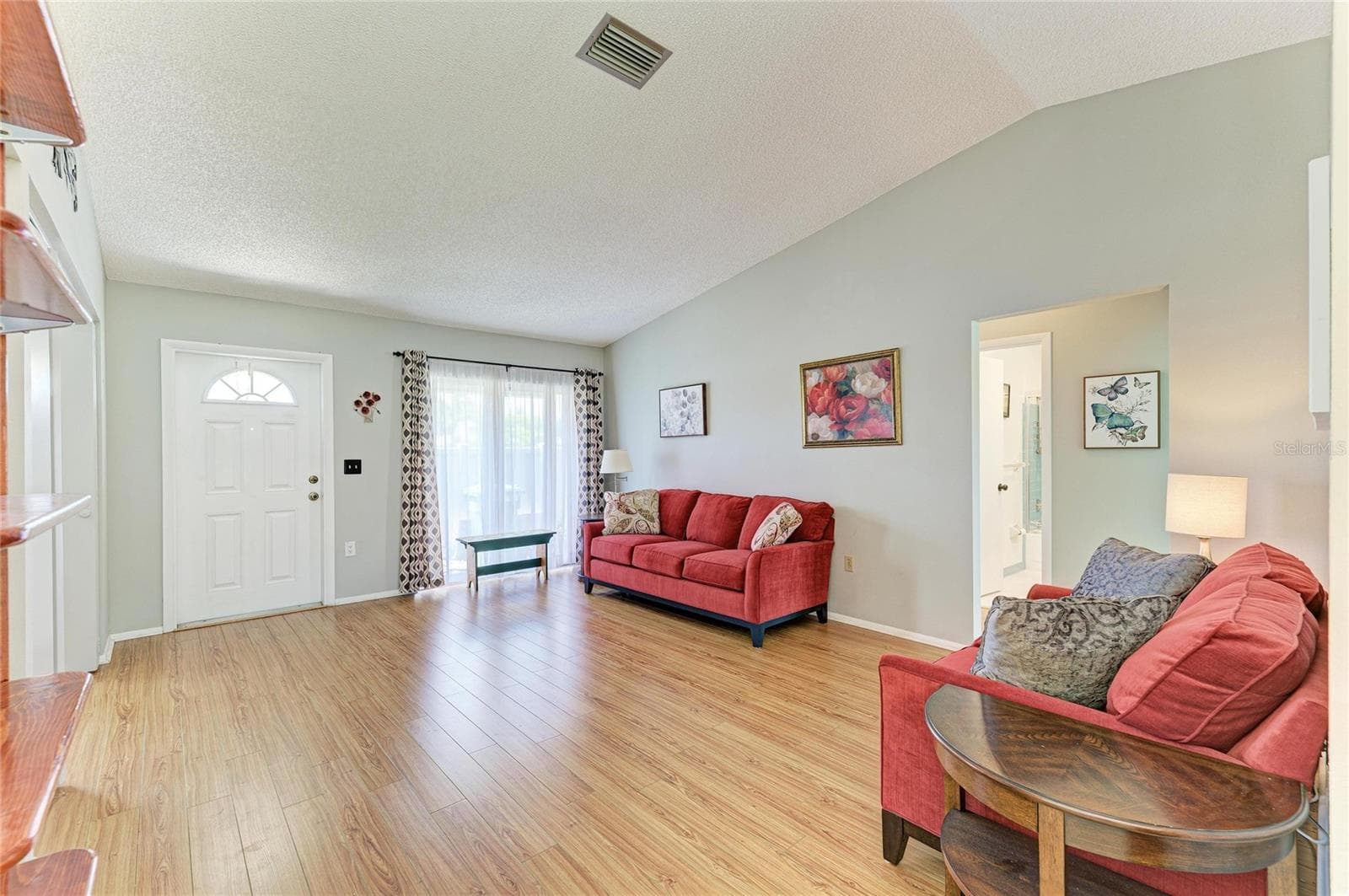 Spacious living room with vaulted ceilings and sliders to the front patio. 3rd bedroom/office/flex room to the left of the front door and hall to the primary bedroom, guest room and guest bathroom to the right. - 3403 36TH ST W #109, BRADENTON