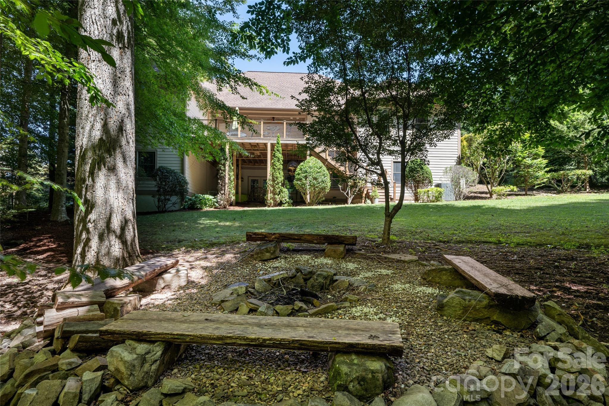 A large, private back yard with firepit, grass and shade, and upper porch with Ipe flooring and a hanging porch bed, partially covered, and basement access from under covered lower area with concrete pad. - 170 Cape Martin Circle, Hendersonville