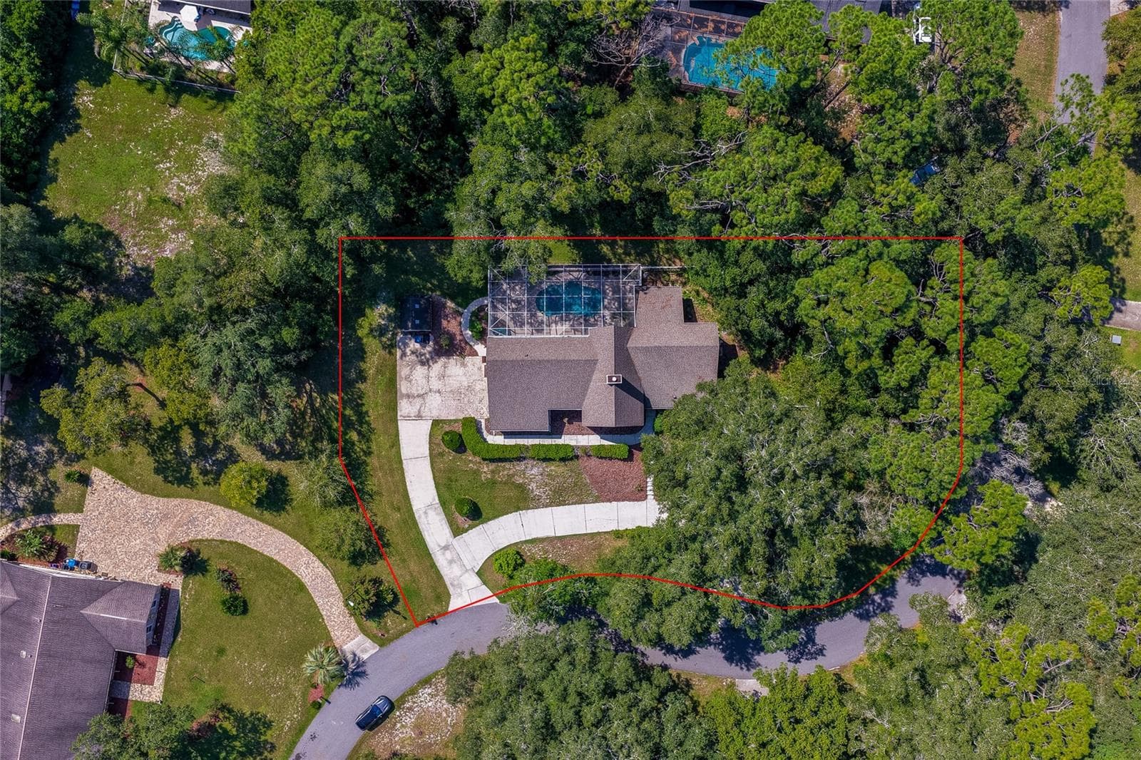 Direct overhead aerial view outlining the home's generous lot boundary surrounded by dense tree cover, a curved driveway, and a private pool enclosure. - 2081 PENNSYLVANIA DR, DELAND