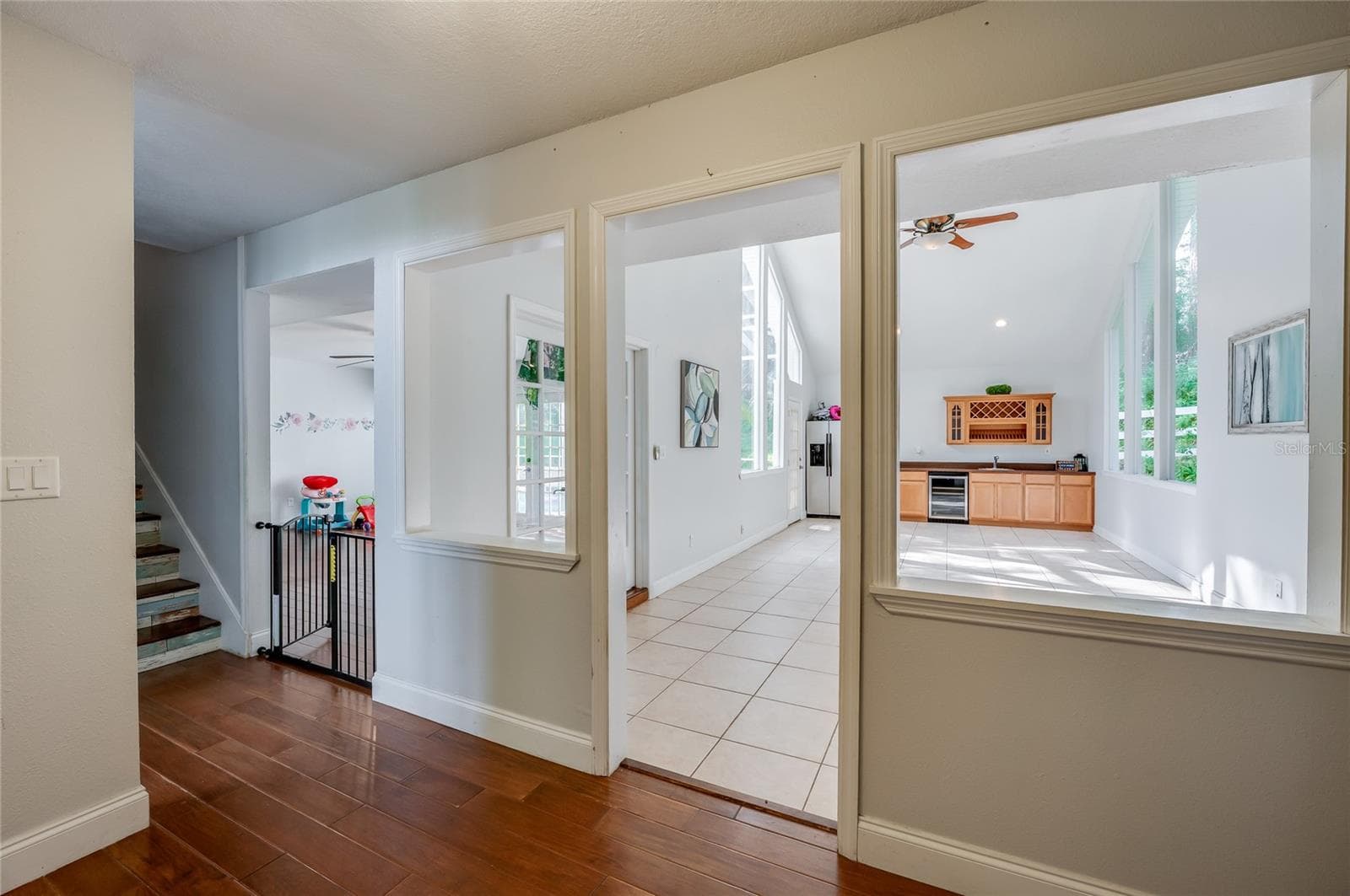 Hallway perspective highlighting warm laminate floors, architectural interior cutouts, and seamless transitions into light-filled open rooms. - 2081 PENNSYLVANIA DR, DELAND