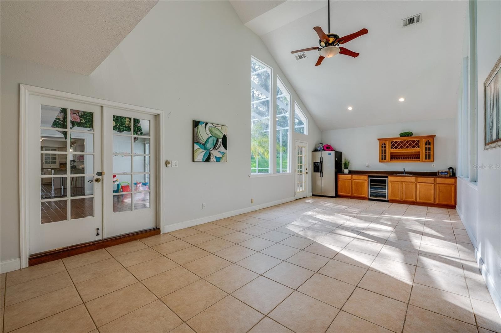 Bright multipurpose living space with soaring vaulted ceilings, skylight-style windows, ceramic tile flooring, and classic French doors. - 2081 PENNSYLVANIA DR, DELAND
