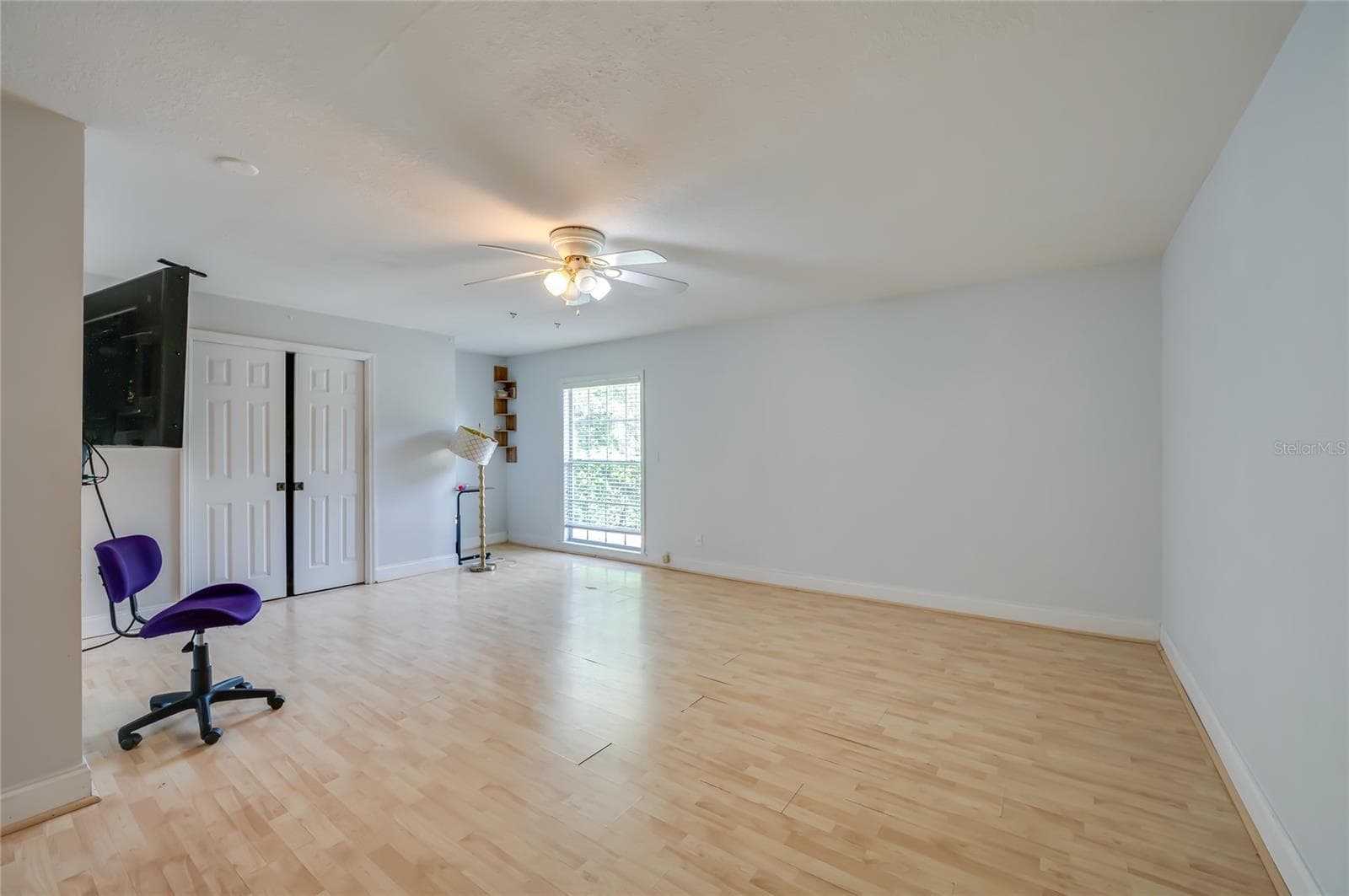 Expansive bedroom room featuring light laminate flooring, soft neutral walls, double-door closet storage, and a large window. - 2081 PENNSYLVANIA DR, DELAND