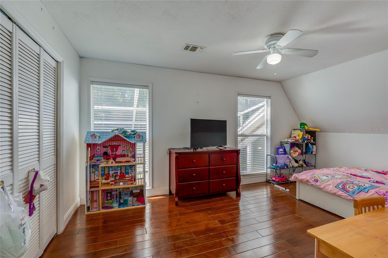 Versatile bedroom space showing warm laminate floors, white closet doors, and natural light from wide windows. - 2081 PENNSYLVANIA DR, DELAND