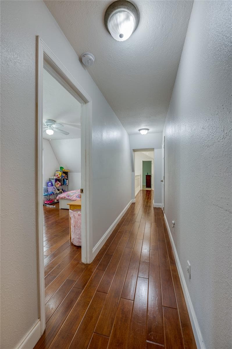 Long interior hallway showcasing polished laminate flooring, recessed ceiling lights, and white trim throughout. - 2081 PENNSYLVANIA DR, DELAND