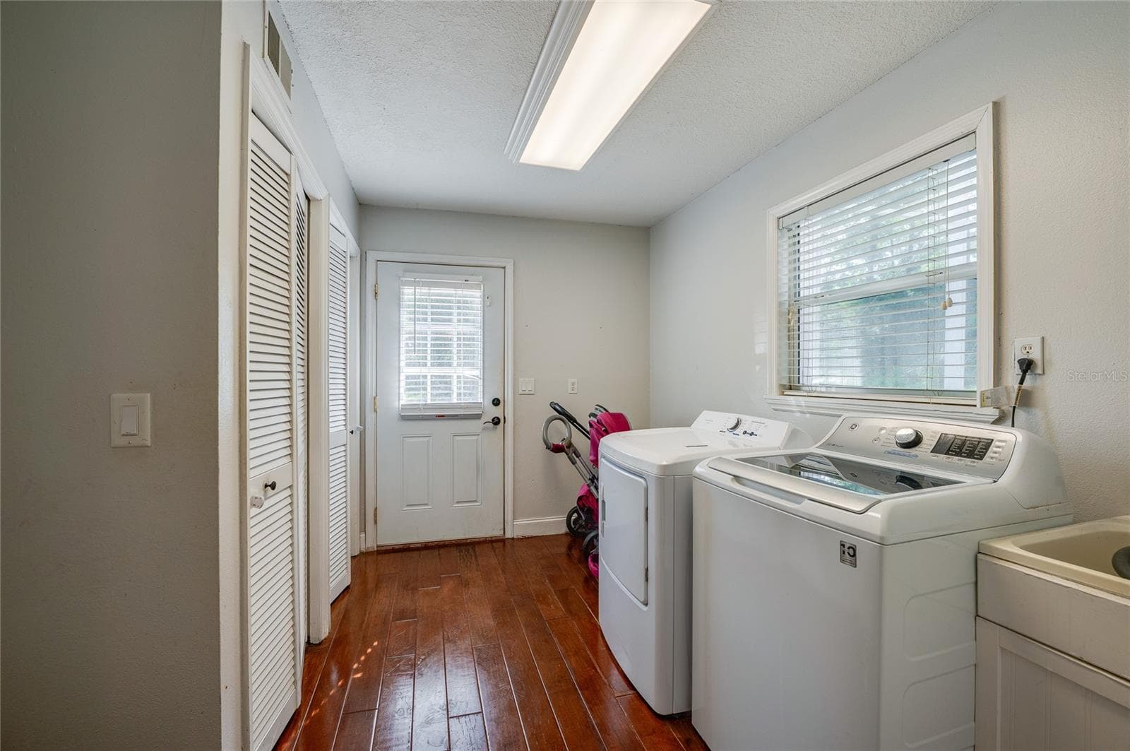 Convenient laundry room equipped with a washer, dryer, utility sink, louvered closet doors, and direct exterior door access. - 2081 PENNSYLVANIA DR, DELAND