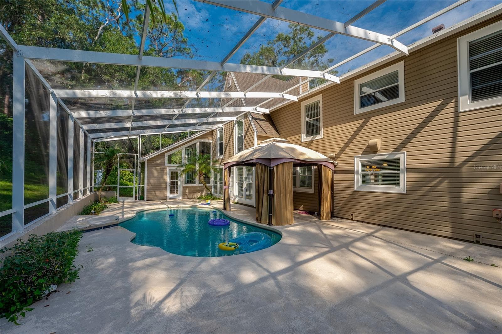 Spacious outdoor patio with a covered gazebo sitting alongside a sparkling, screened-in in-ground pool. - 2081 PENNSYLVANIA DR, DELAND