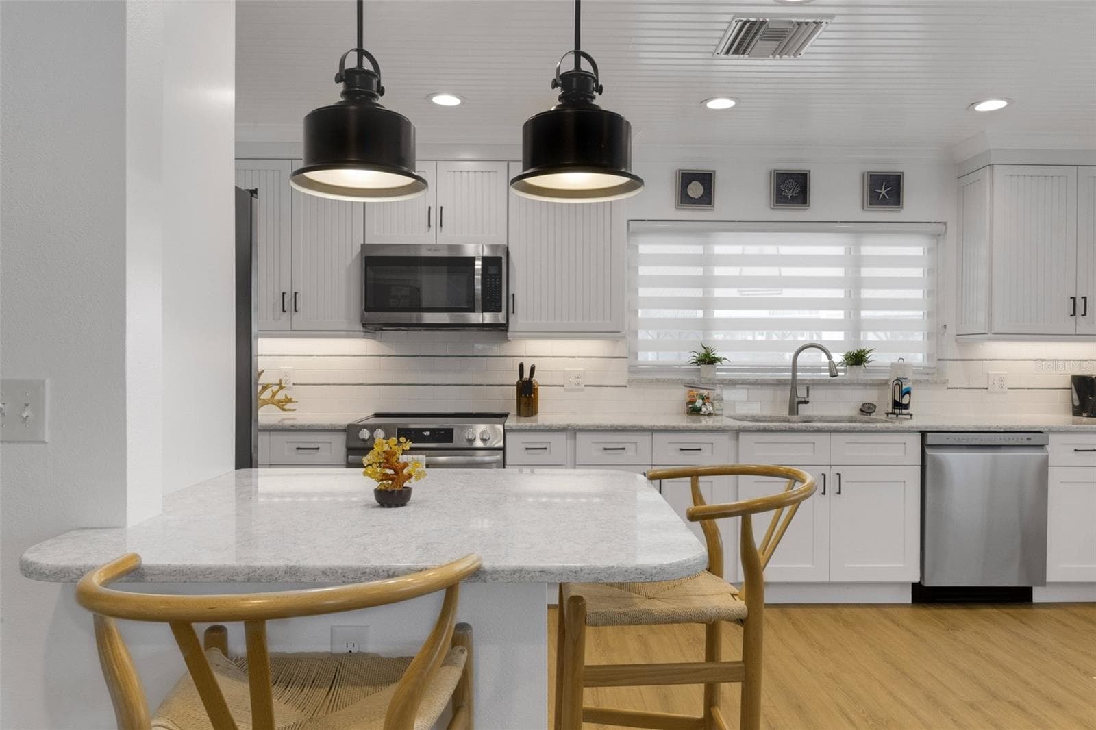Updated kitchen features white cabinetry, stainless steel appliances and a generous breakfast bar. - 18317 SUNSET BLVD, REDINGTON SHORES