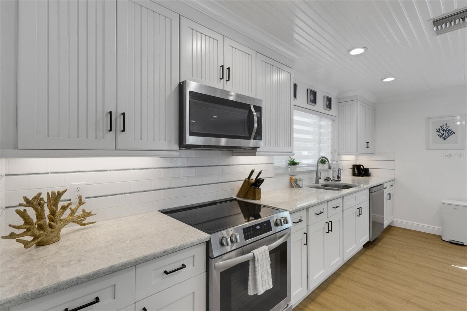 Beautifully updated kitchen with white cabinetry, stainless appliances and coastal inspired finishes. - 18317 SUNSET BLVD, REDINGTON SHORES