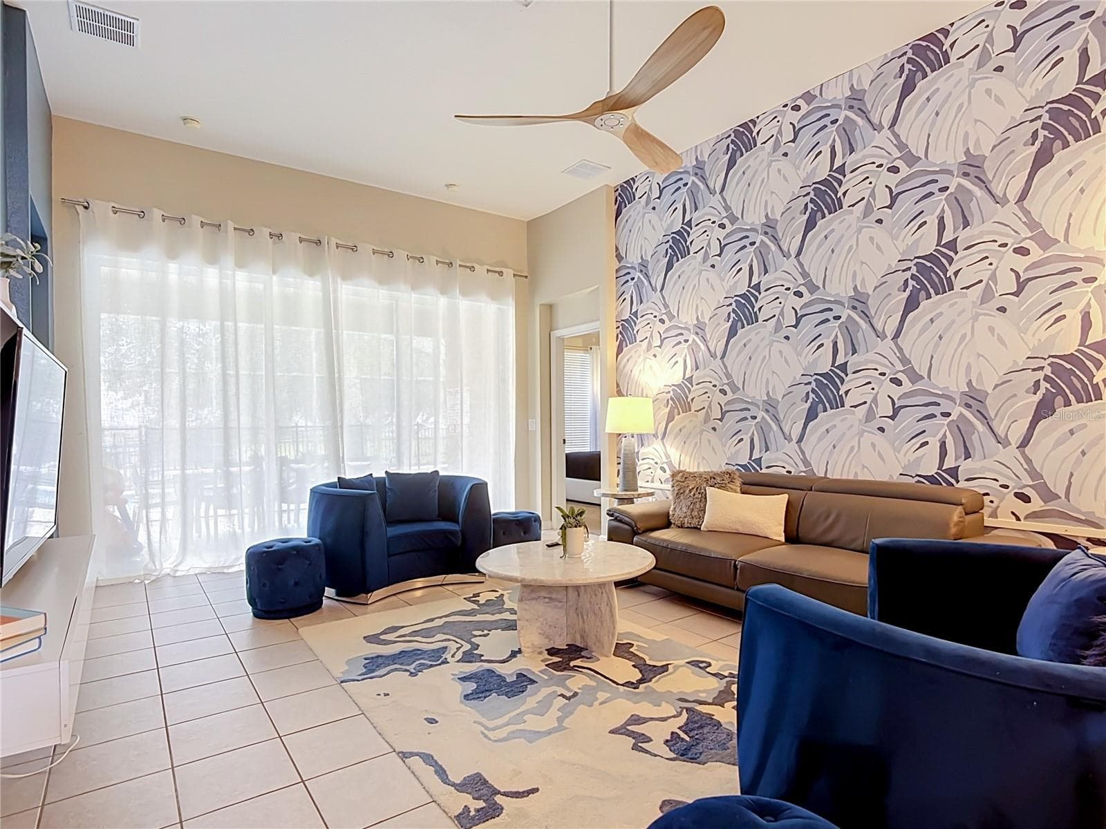 Comfortable living room with sliding glass doors to the pool deck. - 7742 COMROW ST, KISSIMMEE