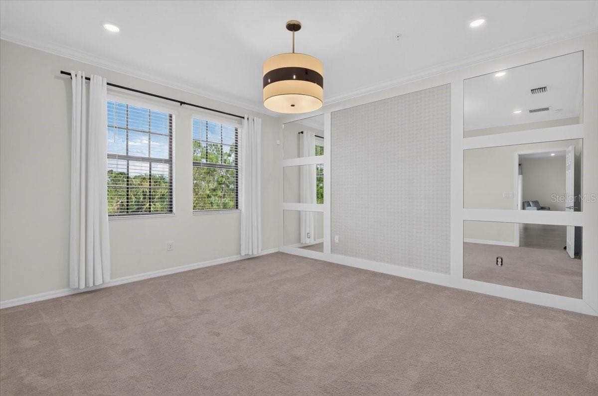 Primary Bedroom with accent wall, light fixture and window treatments - 10059 CROOKED CREEK DR #202, VENICE