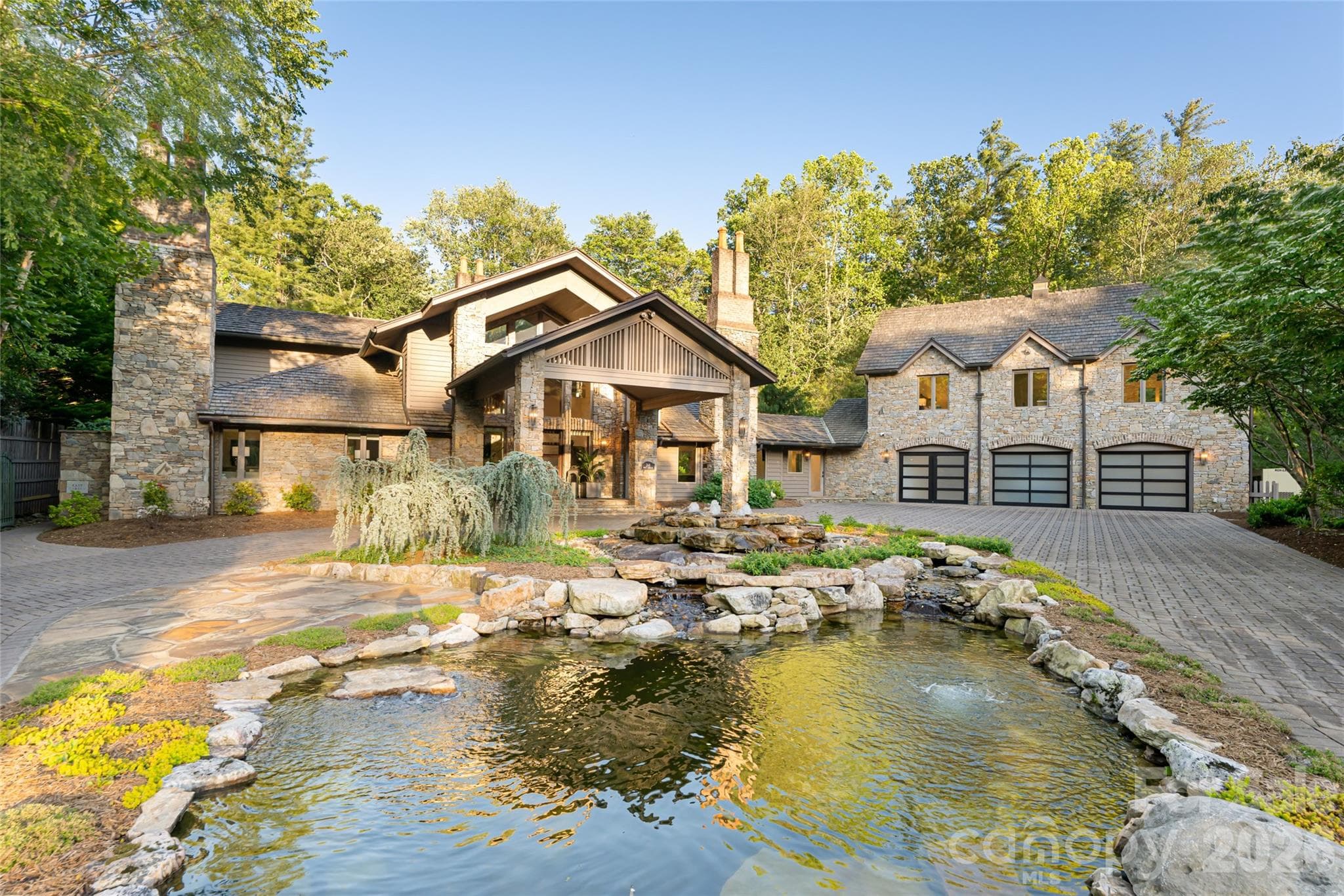 Old-world stone elegance meets modern luxury in this gated, stately residence featuring a circular driveway, grand portico, and tranquil pond.  Main House features a 3 car garage. - Asheville
