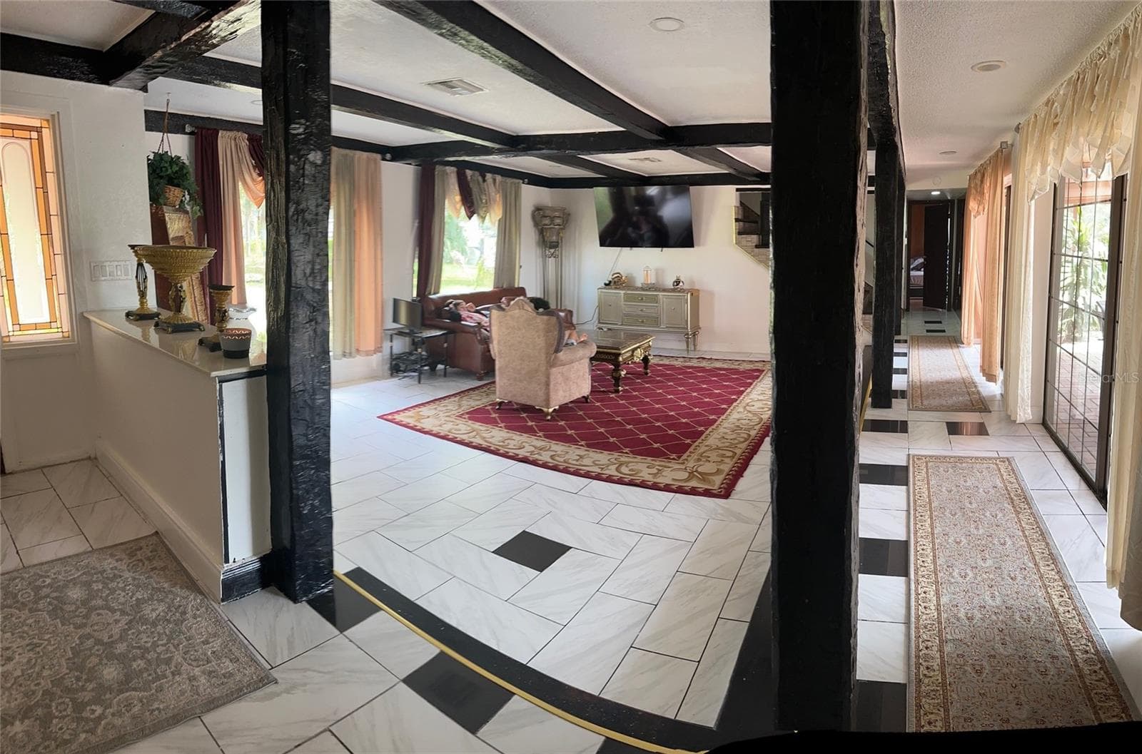 STEP DOWN TO LARGE LIVING ROOM . DOORS TO POOL AREA. HALLWAY TO LIBRARY, 1/2 BATH  AND STAIRWAY TO 4 BEDROOMS AND 3 BATHROOMS - 1238 FLOTILLA DR, HOLIDAY