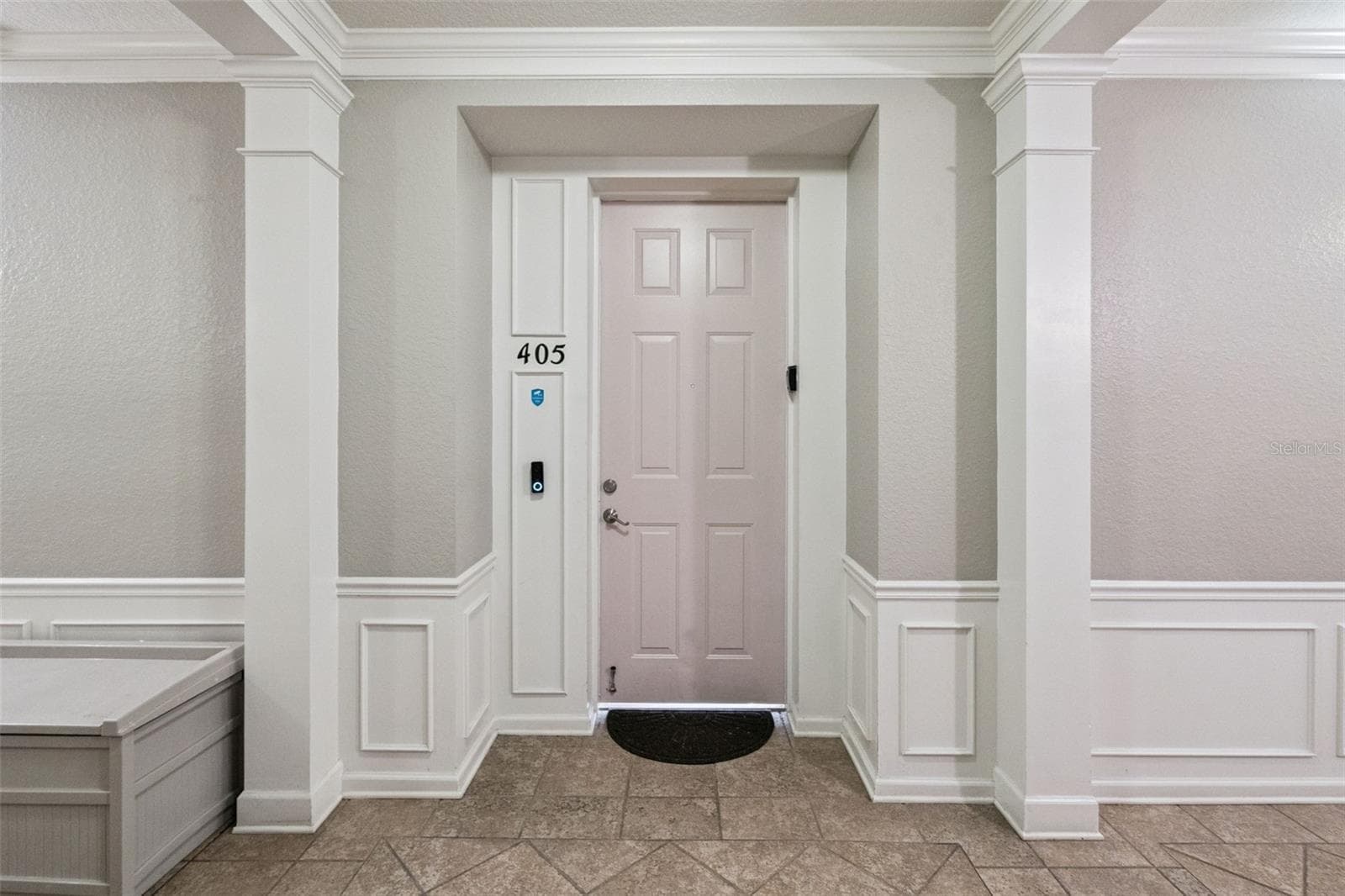 Unit Entrance:Private condo front entrance framed by decorative white columns, detailed wainscoting, and smart video doorbell integration. - 4840 CAYVIEW AVE #405, ORLANDO