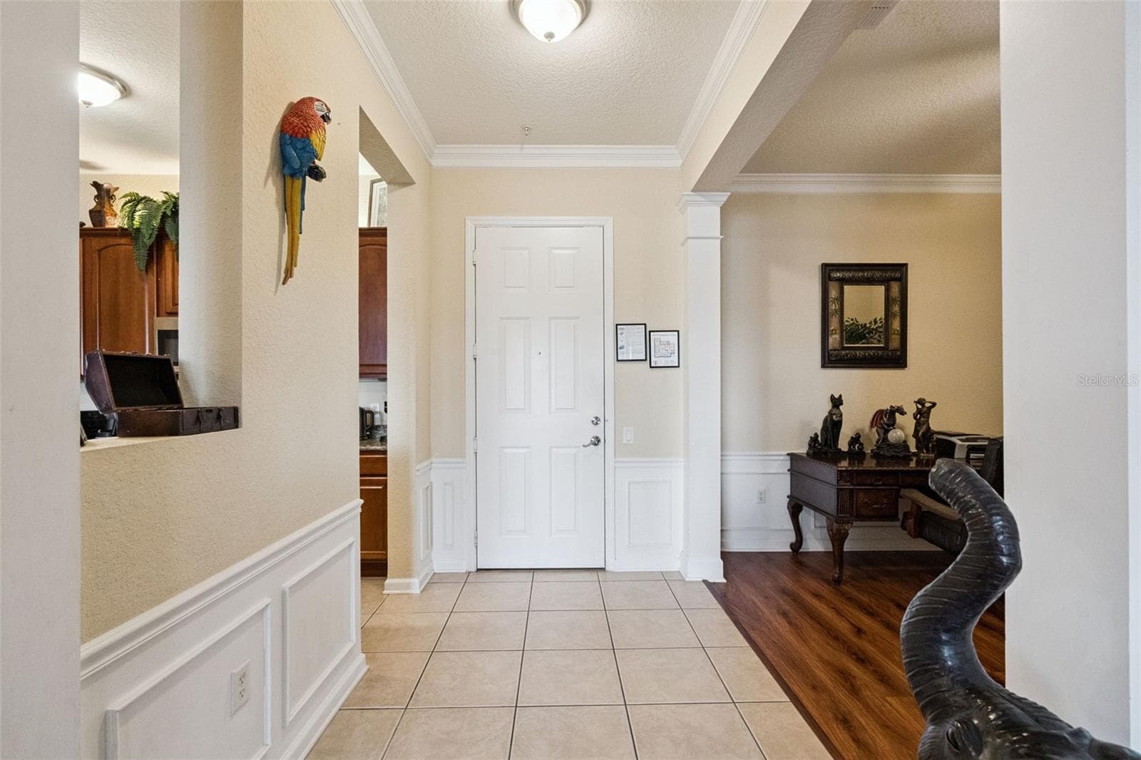 Entry Foyer:Welcoming indoor foyer with neutral tile flooring, crown molding, detailed wainscoting, and seamless flow into adjacent rooms. - 4840 CAYVIEW AVE #405, ORLANDO