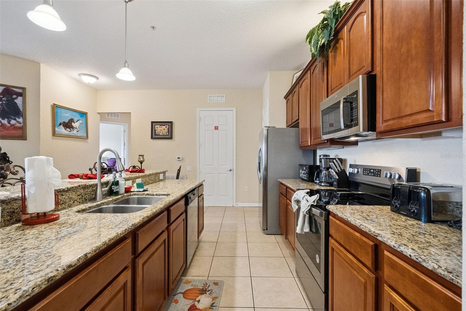 Kitchen Work Corridor:Spacious kitchen area offering abundant cabinet storage, sleek stainless steel appliances, granite surfaces, and easy pass-through connectivity. - 4840 CAYVIEW AVE #405, ORLANDO