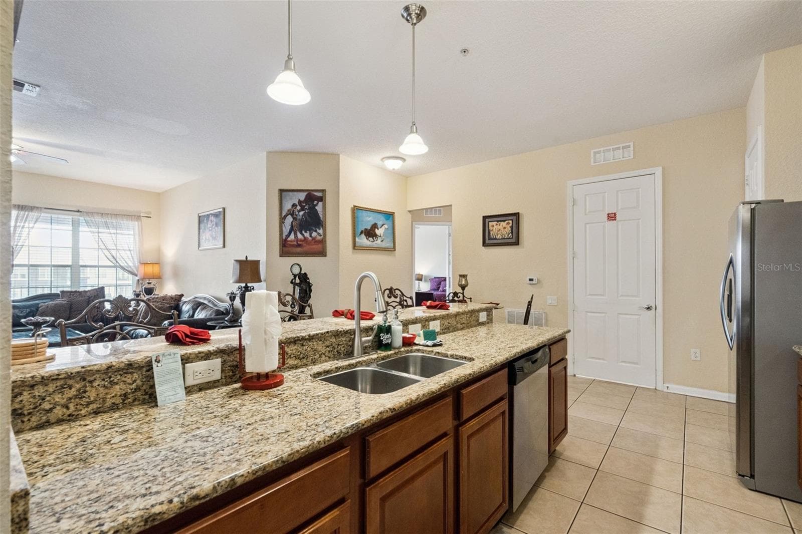 Kitchen Sink & Countertops:Kitchen peninsula equipped with a double-basin stainless steel sink, gooseneck faucet, granite countertops, and pendant lighting. - 4840 CAYVIEW AVE #405, ORLANDO