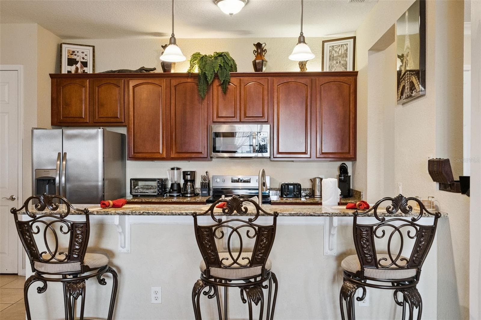 Raised Breakfast Bar:Kitchen peninsula featuring a raised granite breakfast bar with seating for three, pendant lighting, and sleek stainless steel appliances. - 4840 CAYVIEW AVE #405, ORLANDO