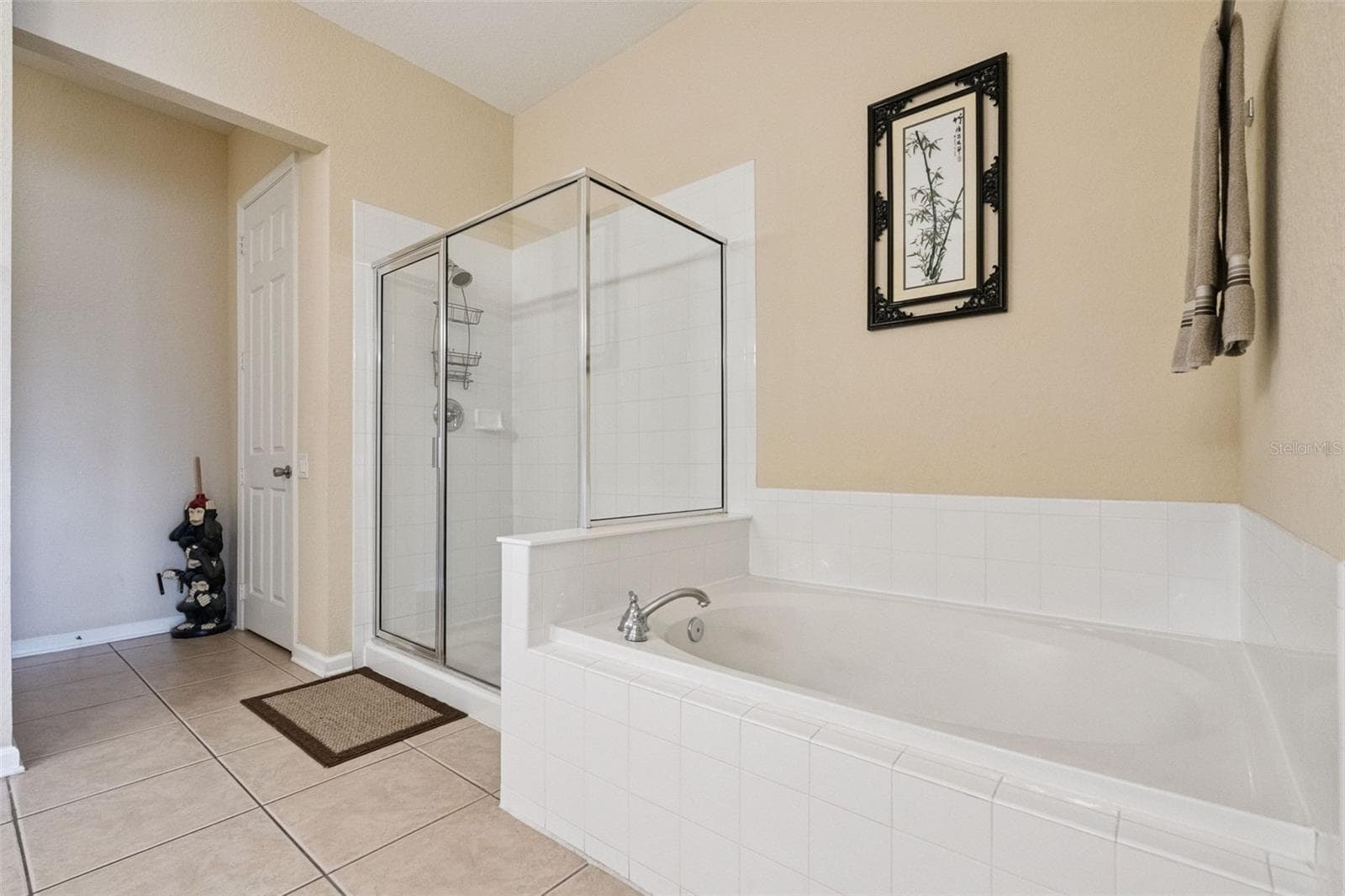 Soaking Tub & Walk-In Shower:Primary bathroom features including a deep soaking tub with white tile surround, separate glass-enclosed shower stall, and neutral tile flooring. - 4840 CAYVIEW AVE #405, ORLANDO