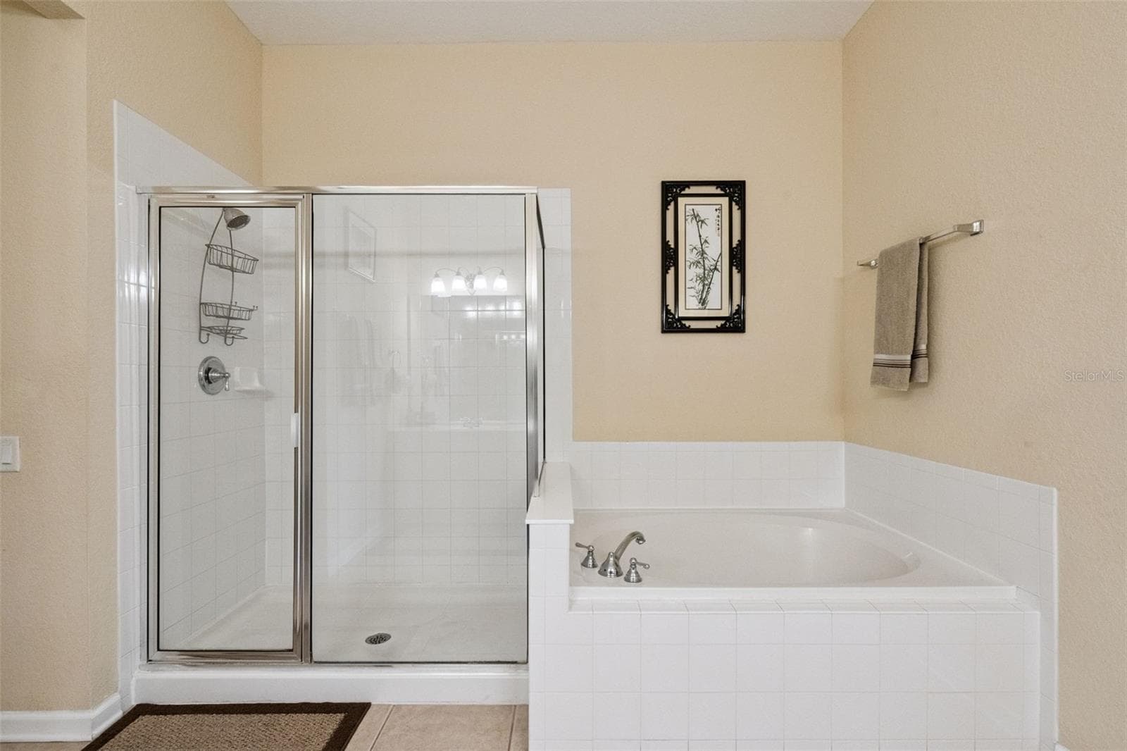 Soaking Tub & Glass Shower:Primary bathroom features highlighting a separate glass-enclosed step-in shower stall and a deep soaking tub framed by white tile work. - 4840 CAYVIEW AVE #405, ORLANDO