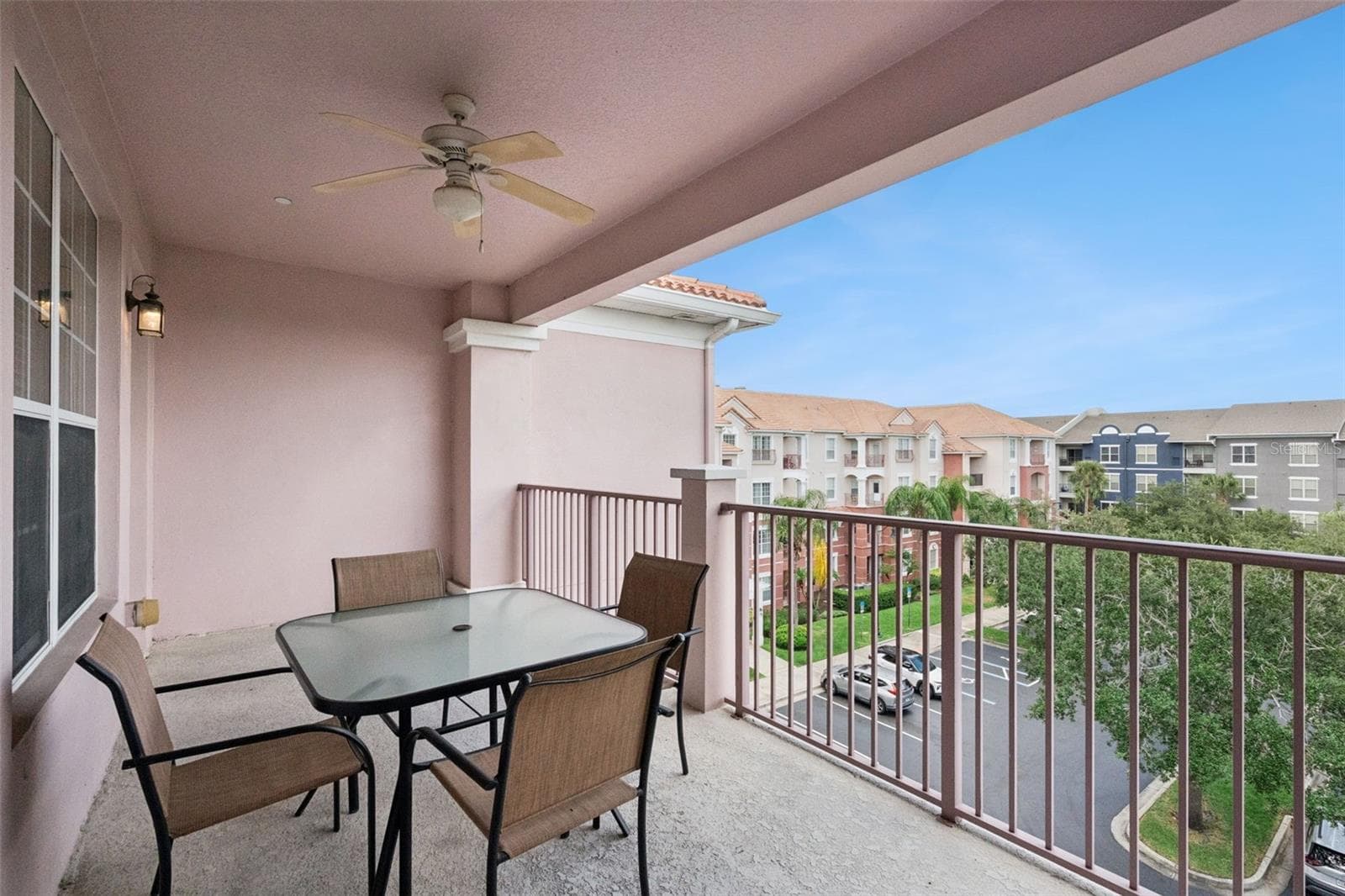 Balcony Dining Area:Covered outdoor living space featuring a glass-top dining table, overhead fan, and open views of the lush resort surroundings. - 4840 CAYVIEW AVE #405, ORLANDO