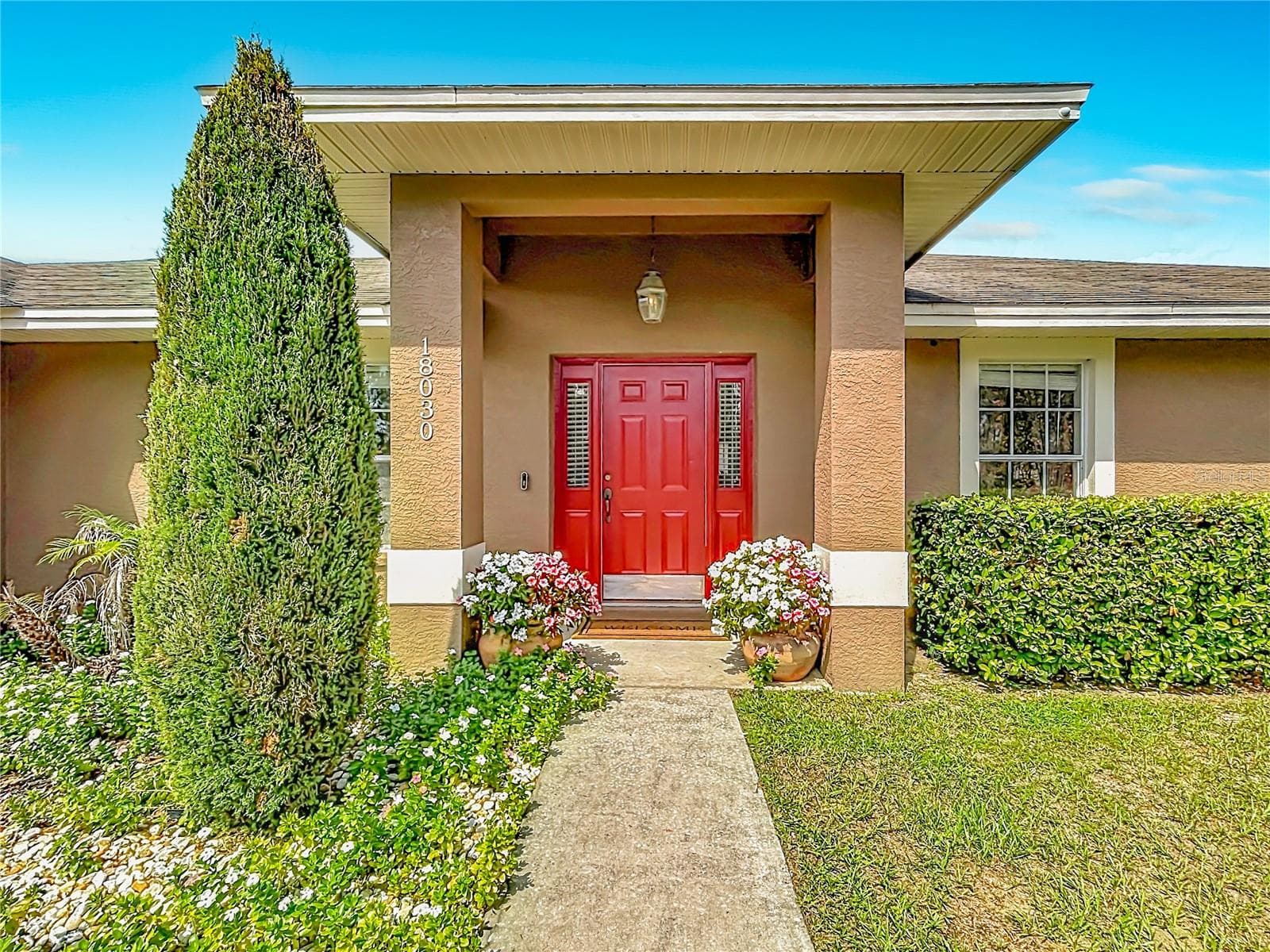 Colorful flowers frame the front entrance, creating a charming and welcoming arrival - 18030 BAYAMON AVE, POLK CITY