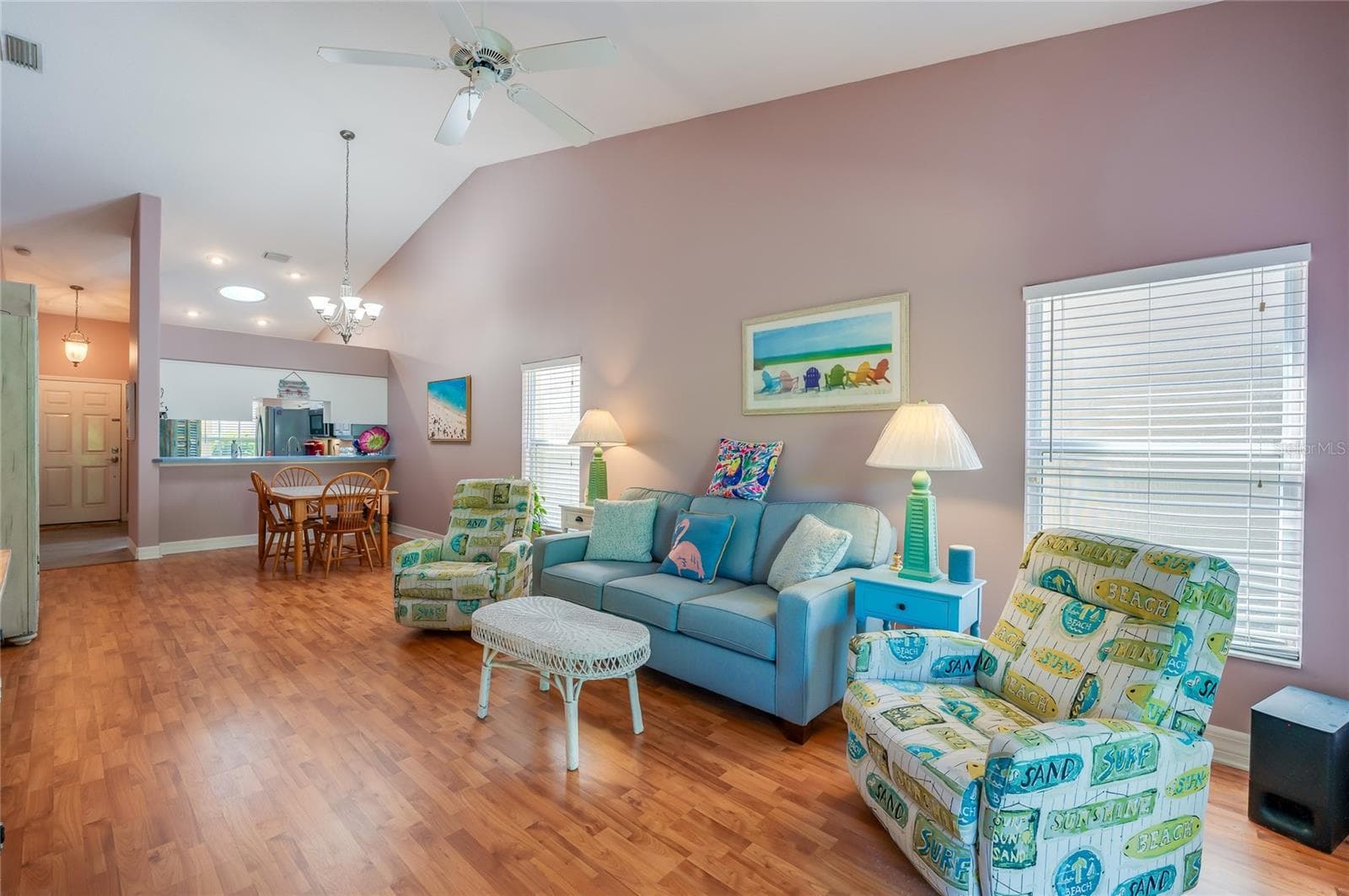 Expansive open-concept main living area defined by high ceilings and continuous laminate flooring. Large windows flood the space with natural light, connecting the front entry, kitchen pass-through, and living space. - 1413 COCONUT PALM CIR, PORT ORANGE