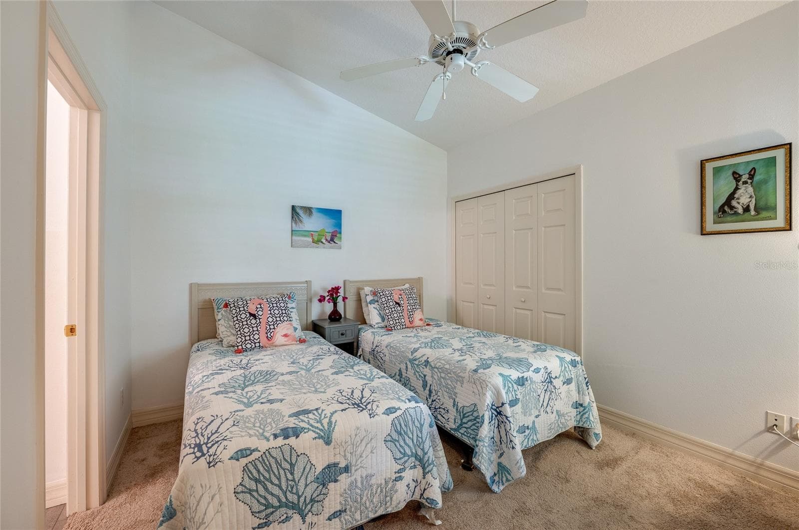 Bright bedroom showcasing vaulted ceilings, plush neutral carpeting, and a white ceiling fan. A bi-fold closet door accentuate the clean, airy layout. - 1413 COCONUT PALM CIR, PORT ORANGE
