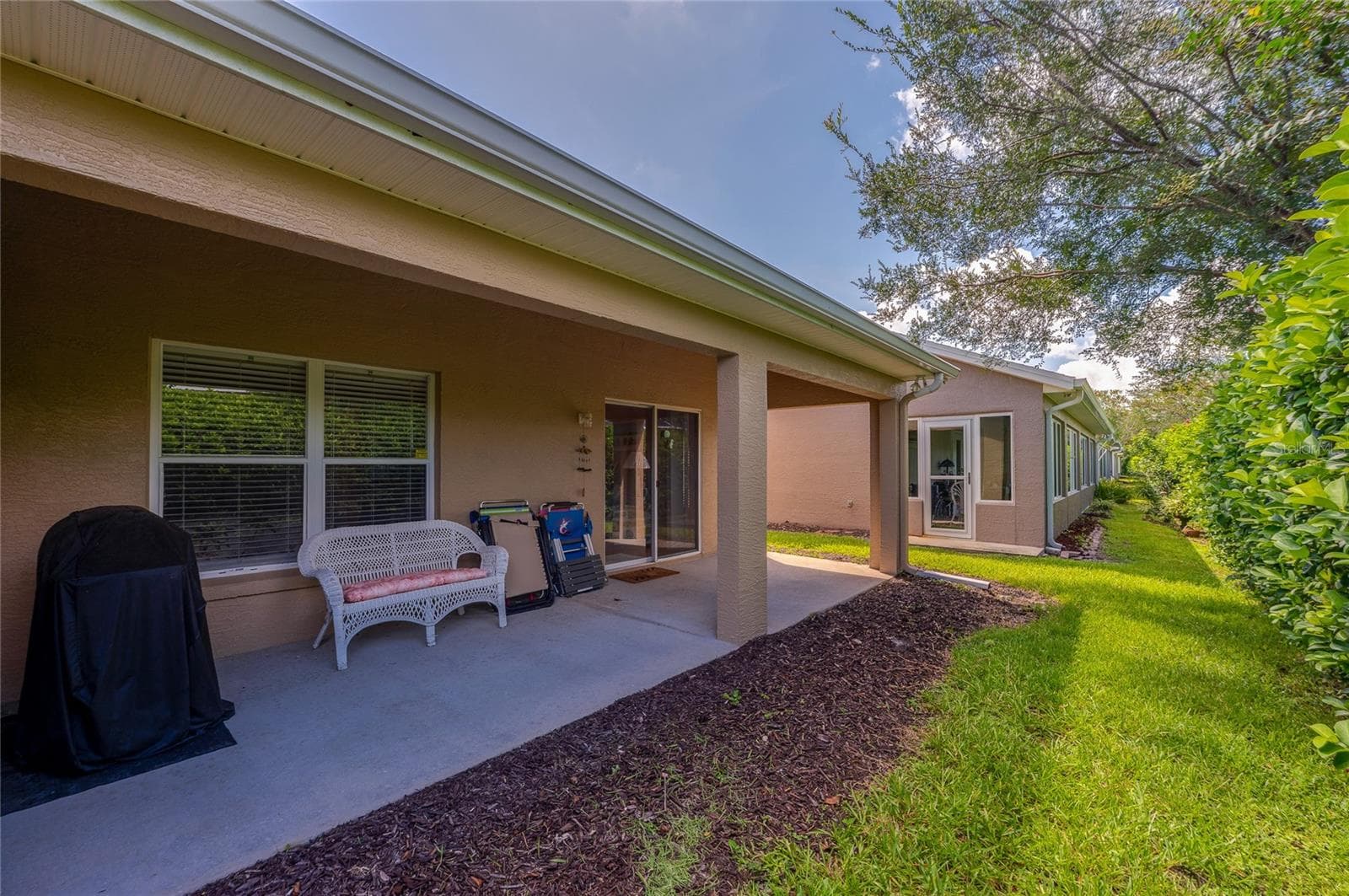 Sheltered back patio with concrete flooring leading out to a lush lawn area. Large glass sliding doors and windows provide easy indoor-outdoor flow along the exterior. - 1413 COCONUT PALM CIR, PORT ORANGE