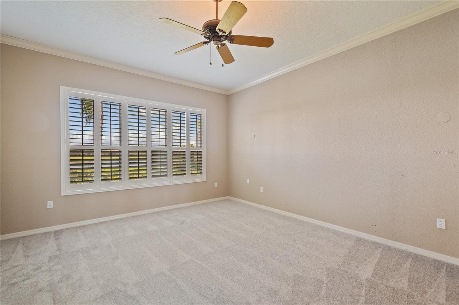 The first-floor primary suite also has a large bank of windows with plantation shutters and a view of the water. - 2464 LAUREL GLEN DR, LAKELAND