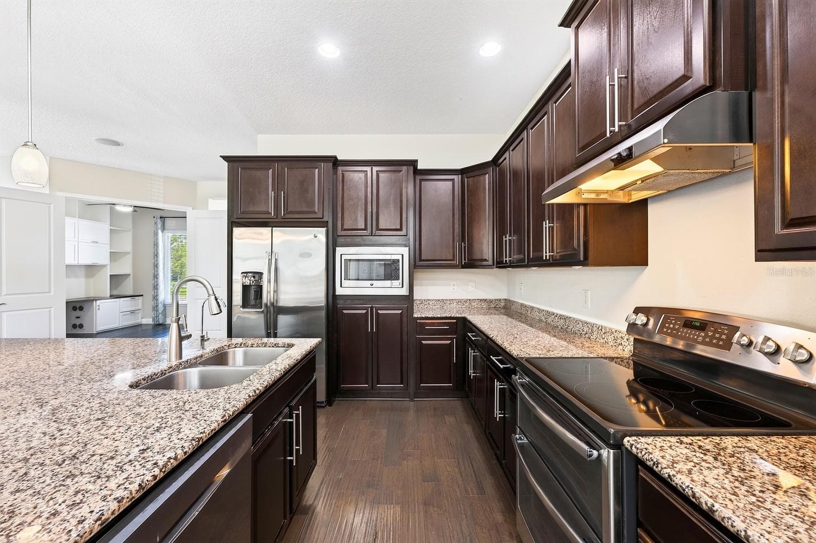 The gorgeous kitchen delivers incredible storage with rich cabinetry extending into the dining area, granite countertops, STAINLESS STEEL APPLIANCES, recessed and pendant lighting, and a large CENTER ISLAND with an extended breakfast table. - 8130 LAUREATE BLVD, ORLANDO