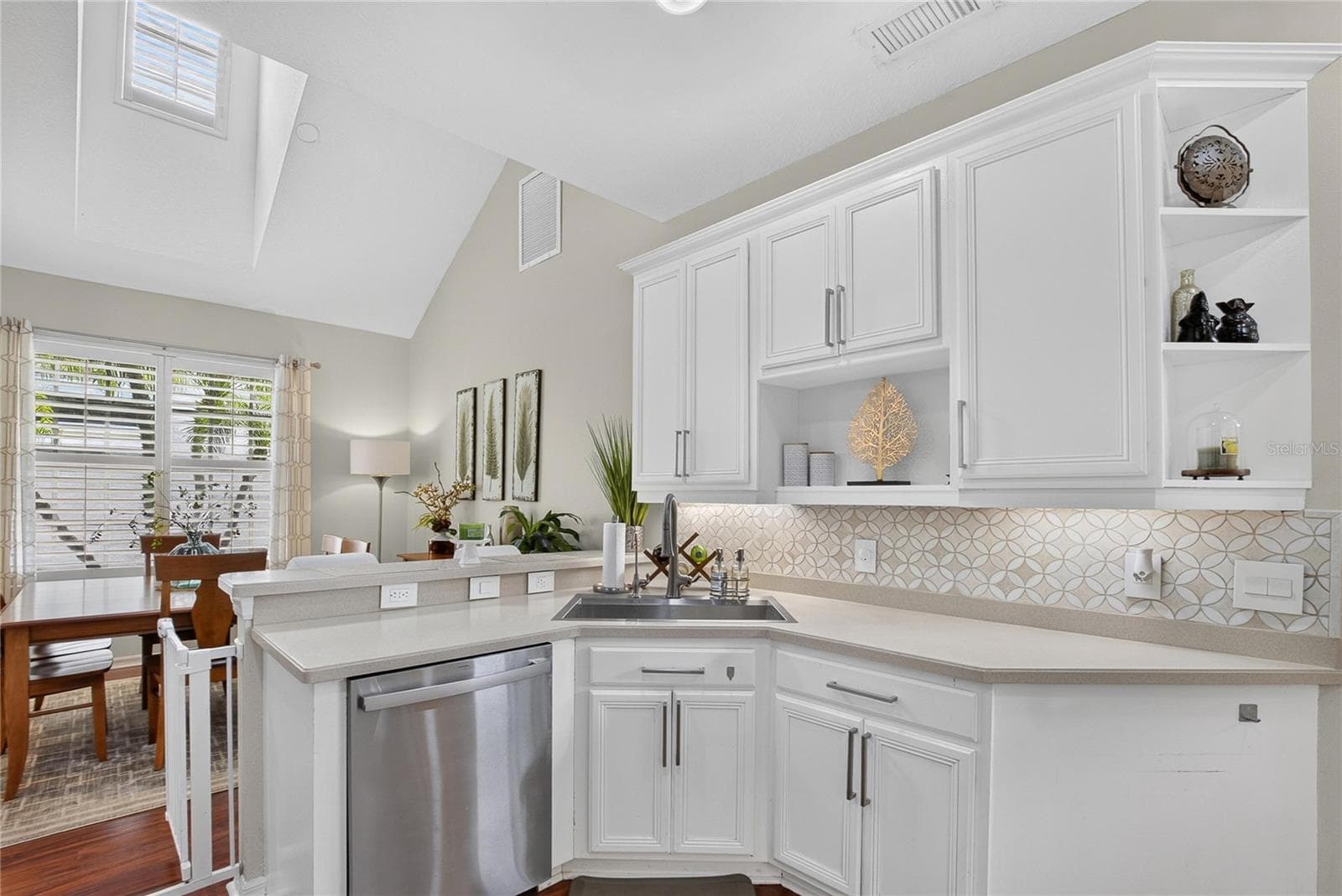 Bright, open kitchen with white cabinetry, decorative backsplash and breakfast bar overlooking the dining area. - 10807 SIERRA VISTA PL, TAMPA