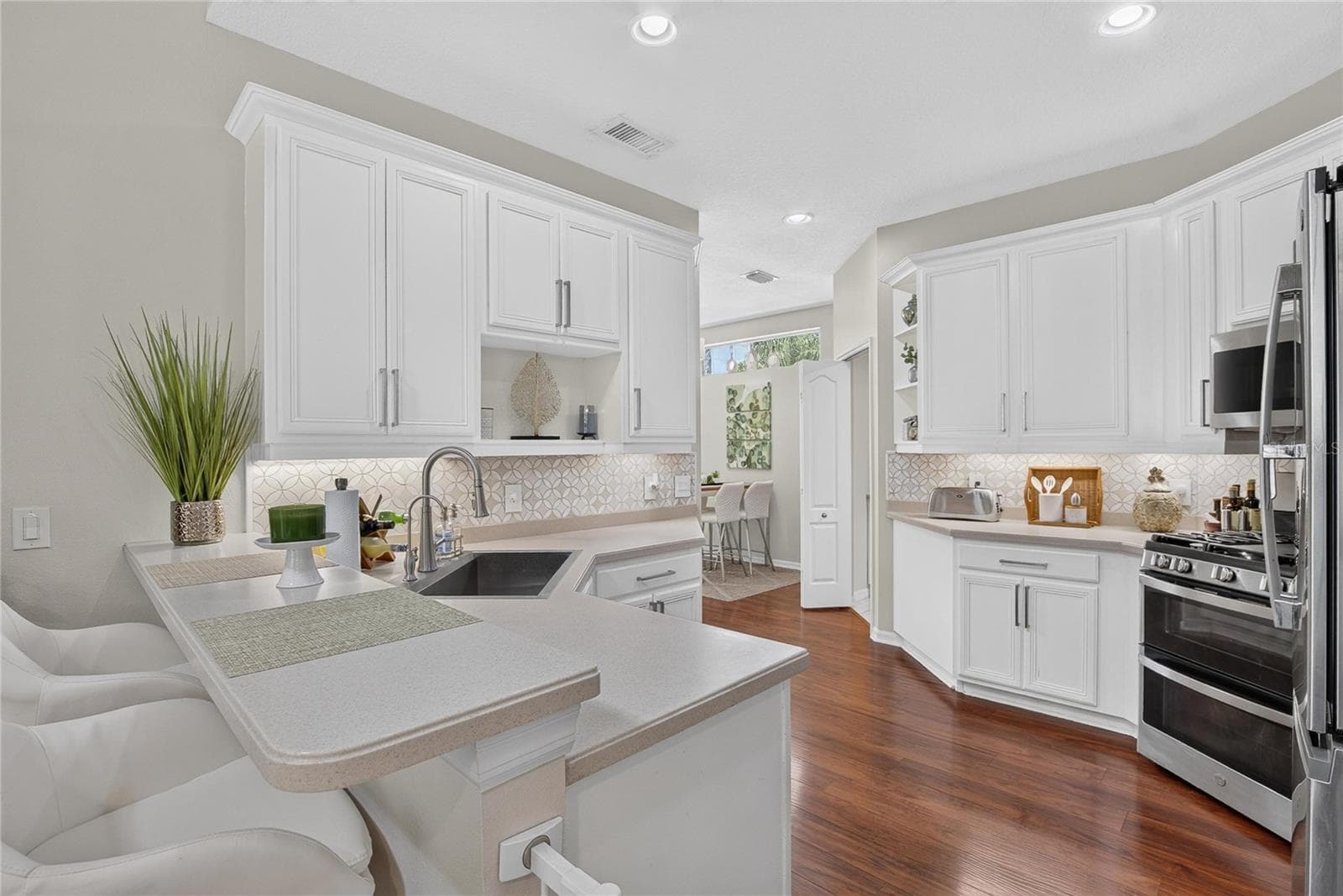 Bright kitchen with white cabinetry, stainless appliances, breakfast bar and abundant counter space. - 10807 SIERRA VISTA PL, TAMPA