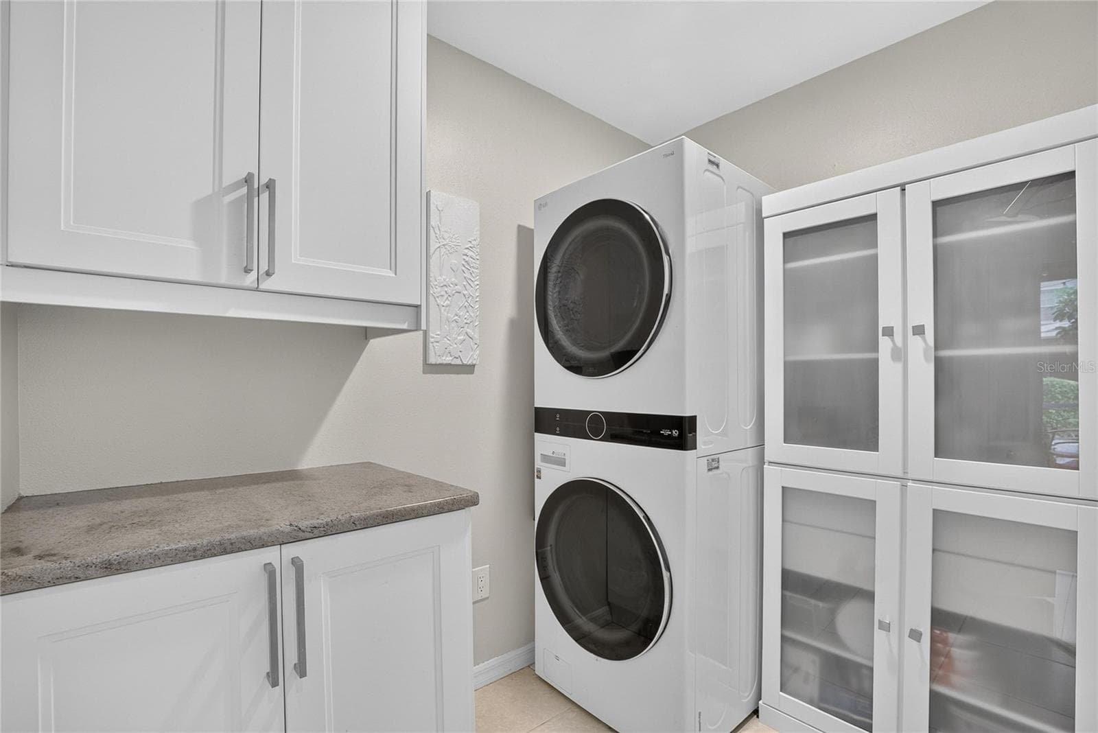 Well-appointed laundry room with stacked washer and gas dryer, abundant cabinetry, counter space and additional storage. - 10807 SIERRA VISTA PL, TAMPA