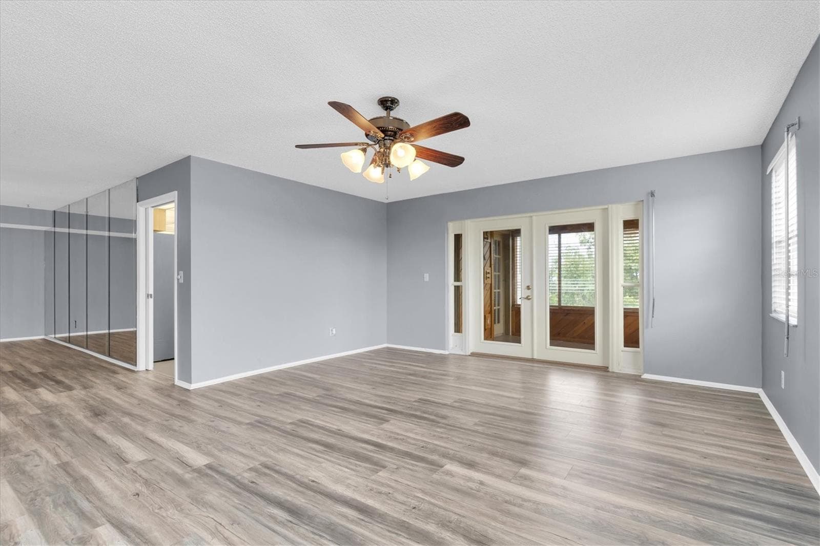 Living area with the doorway into the kitchen and French doors leading to the all season patio. - 8198 TERRACE GARDEN DR #511, ST PETERSBURG
