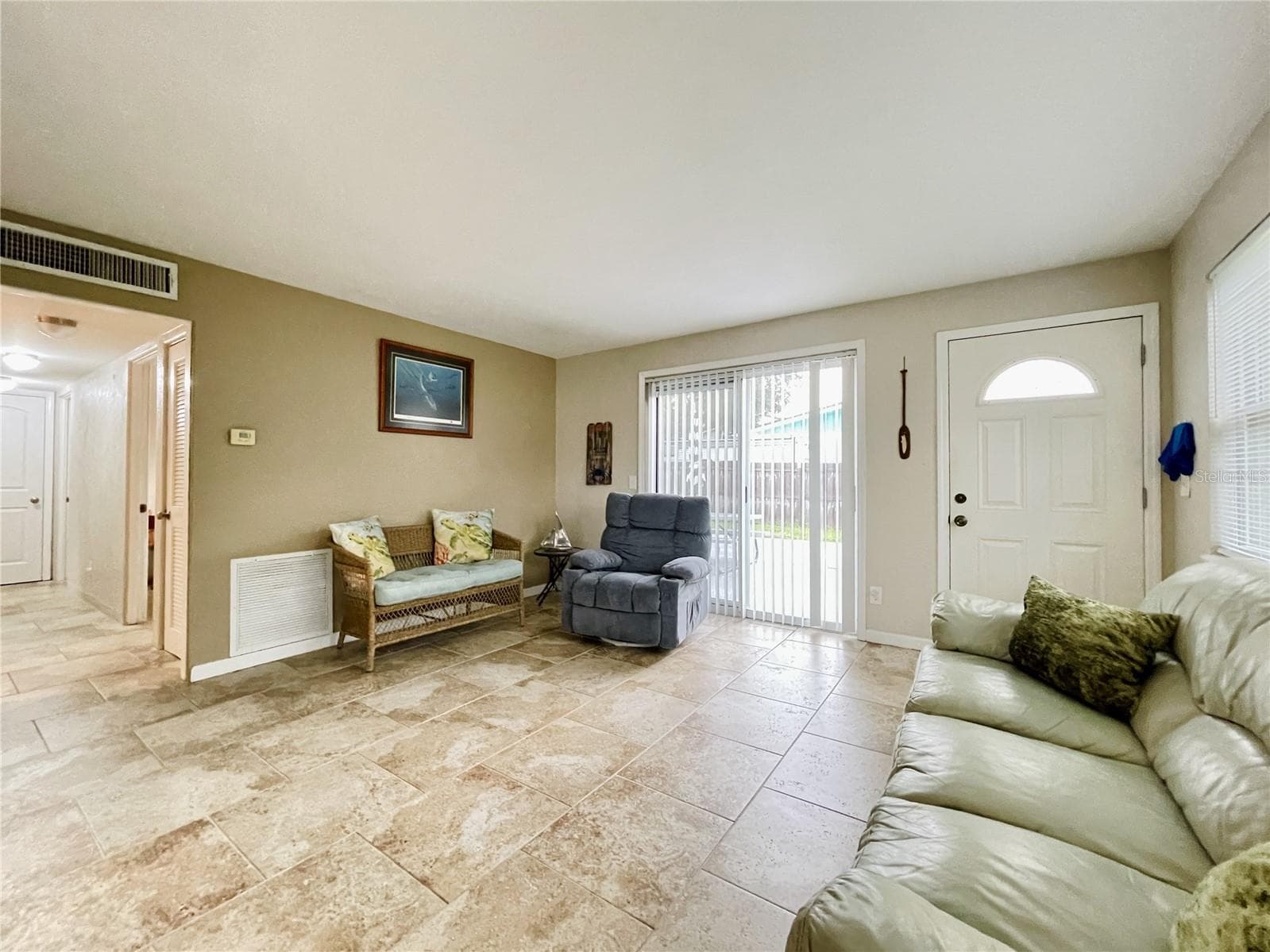 Sunlit living space highlighting a sliding glass door that leads to the backyard. - 723 STEELE AVE, SOUTH DAYTONA