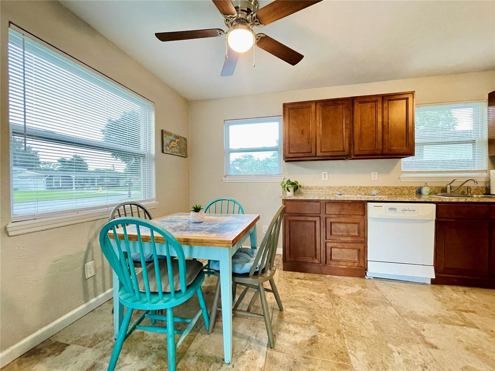 Charming dining niche featuring a vibrant blue table setup tucked next to an expansive kitchen counter with warm wood cabinetry. - 723 STEELE AVE, SOUTH DAYTONA