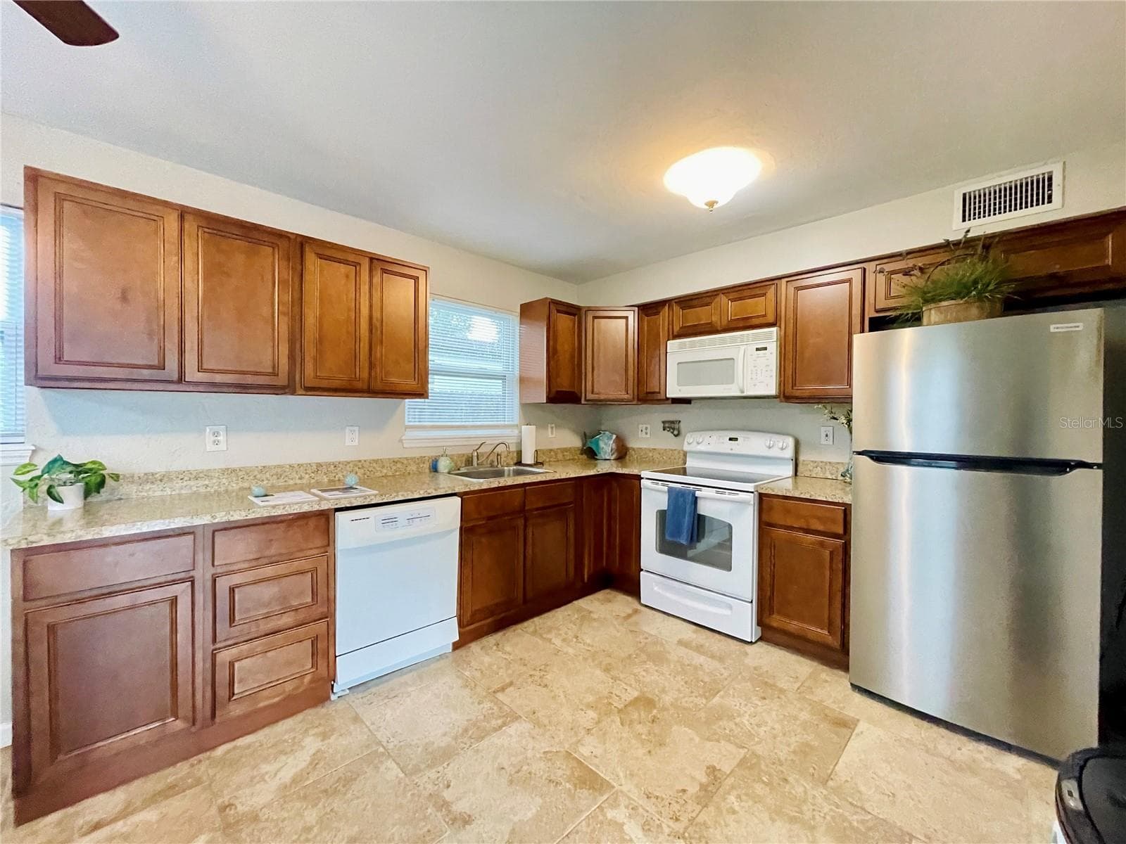 Fully equipped, efficient kitchen showcasing ample countertops and classic wood cabinets. - 723 STEELE AVE, SOUTH DAYTONA