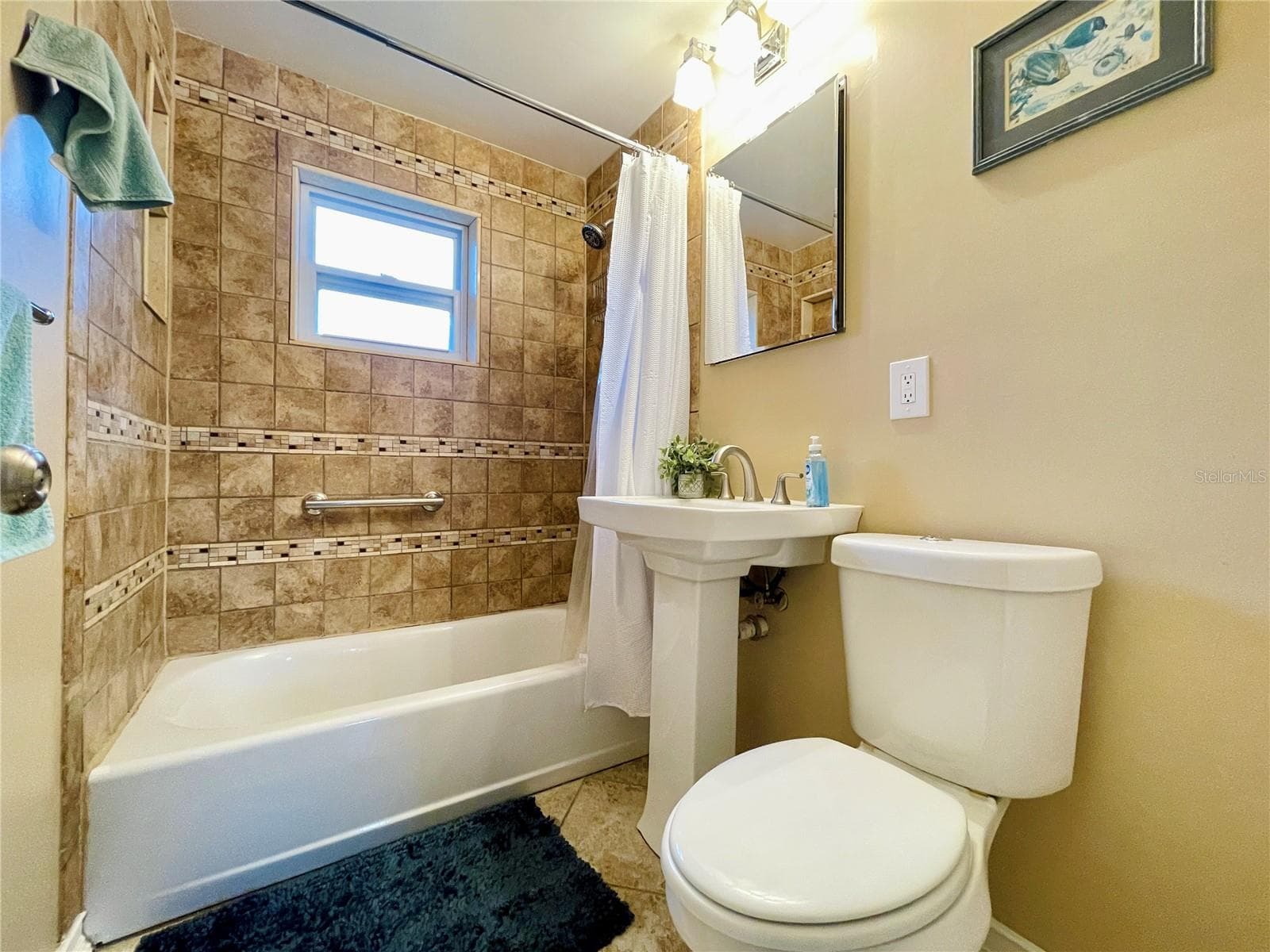 Full bathroom accented by floor-to-ceiling wall tiles, a classic pedestal sink, and a combination bathtub and shower. - 723 STEELE AVE, SOUTH DAYTONA