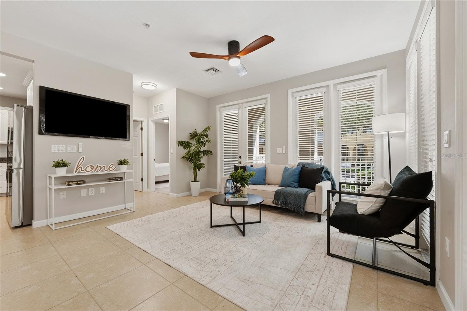 Bright, open living area surrounded by windows and French doors, bringing in abundant natural light. - 1674 LAKEMONT AVE #101, ORLANDO