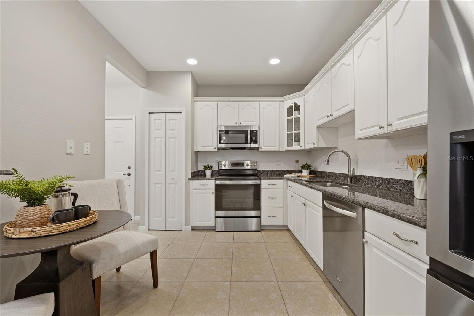 Well-appointed kitchen with white cabinetry, granite countertops, stainless-steel appliances and a casual dining area. - 1674 LAKEMONT AVE #101, ORLANDO