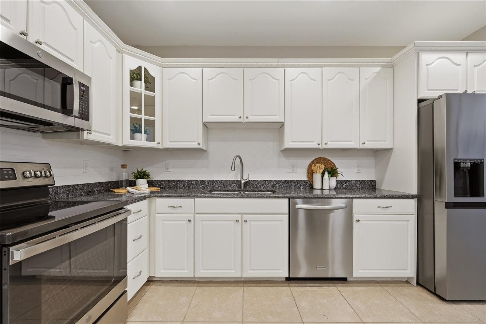 Crisp white cabinetry, granite countertops, tile backsplash and stainless-steel appliances complete the spacious kitchen. - 1674 LAKEMONT AVE #101, ORLANDO