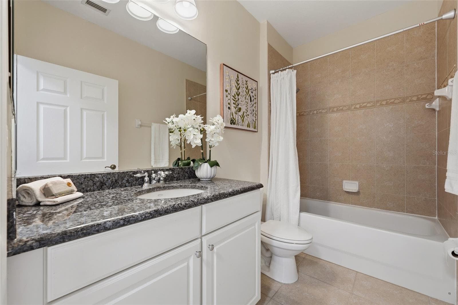 Full guest bathroom features granite countertop, white cabinetry and tiled tub/shower surround. - 1674 LAKEMONT AVE #101, ORLANDO