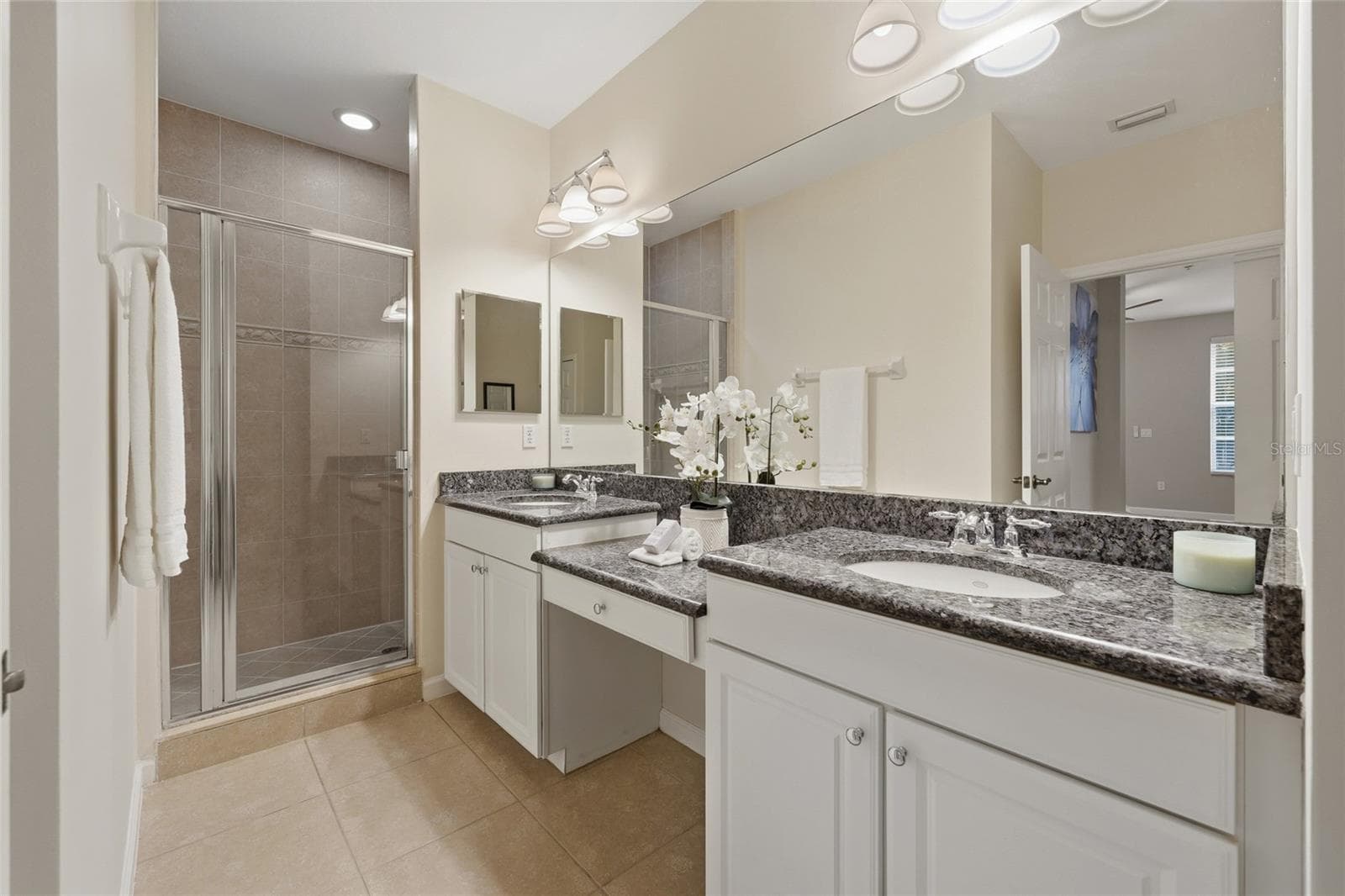 Primary bathroom features dual vanities, granite countertops, separate tiled shower and generous counter space. - 1674 LAKEMONT AVE #101, ORLANDO