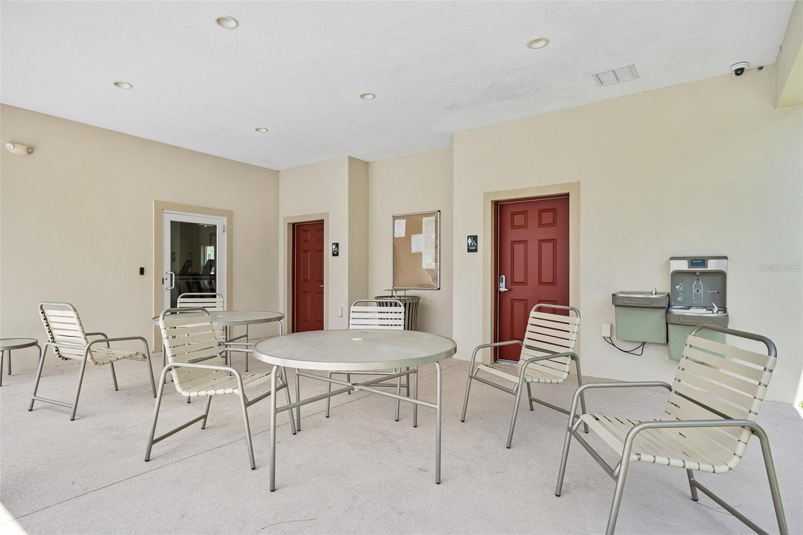 Community seating near pool, access to gym and bathrooms in background - 166 REENA DR, DAYTONA BEACH