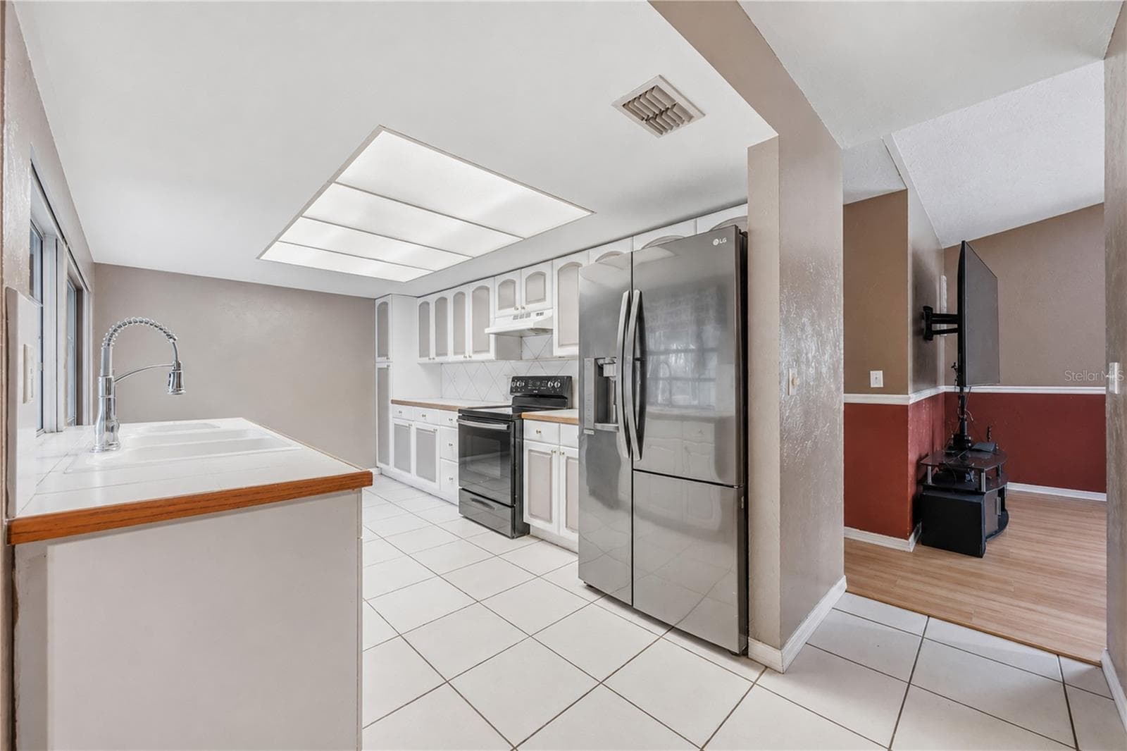 Functional galley kitchen with stainless steel appliances, tile flooring, generous counter space, and seamless view into the adjacent living space. - 3906 SANTIAGO ST, SEBRING