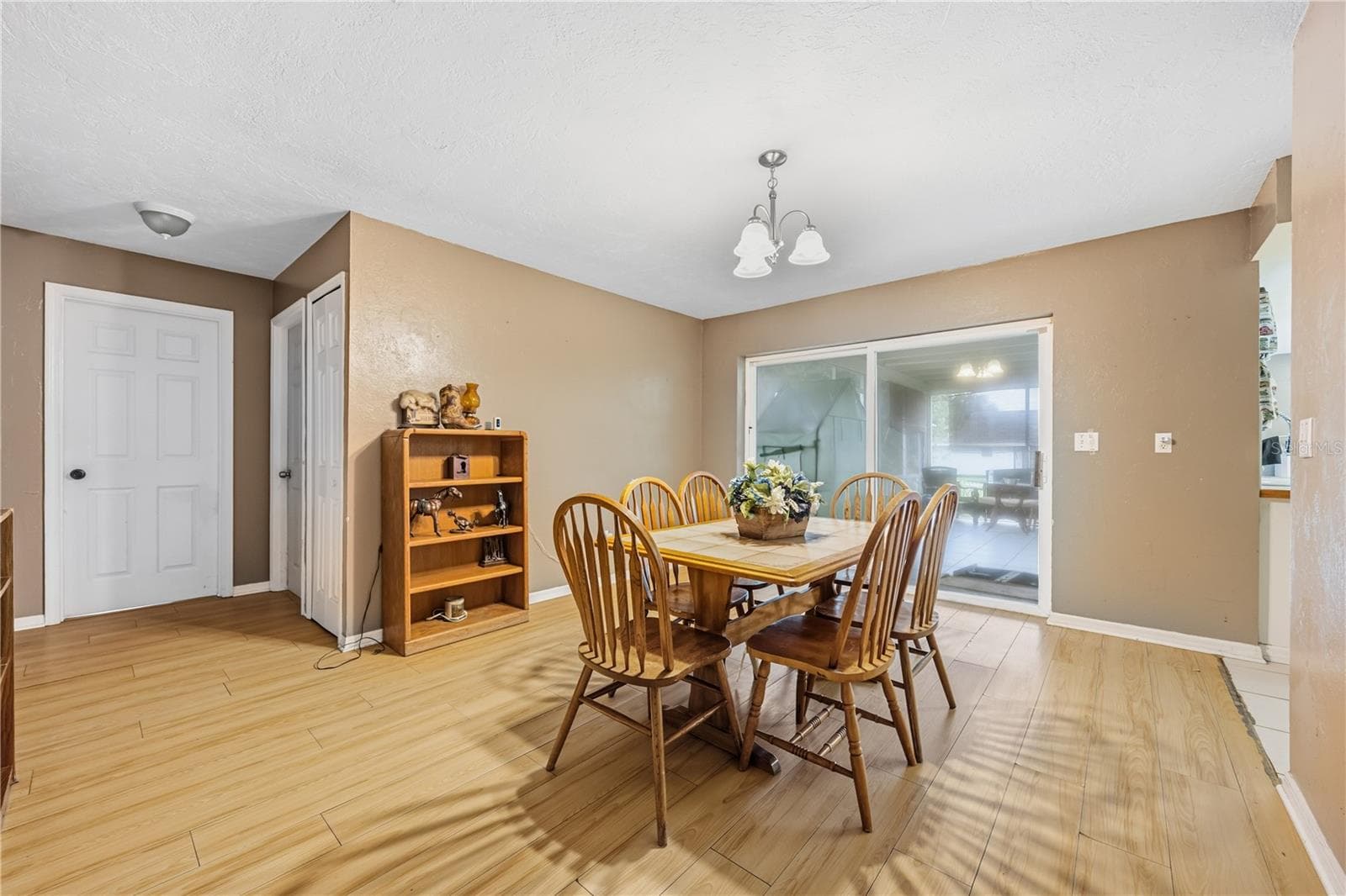 Bright and open dining area located off the main living space, showcasing wood-look laminate flooring and a direct view of the kitchen and hallway. - 3906 SANTIAGO ST, SEBRING