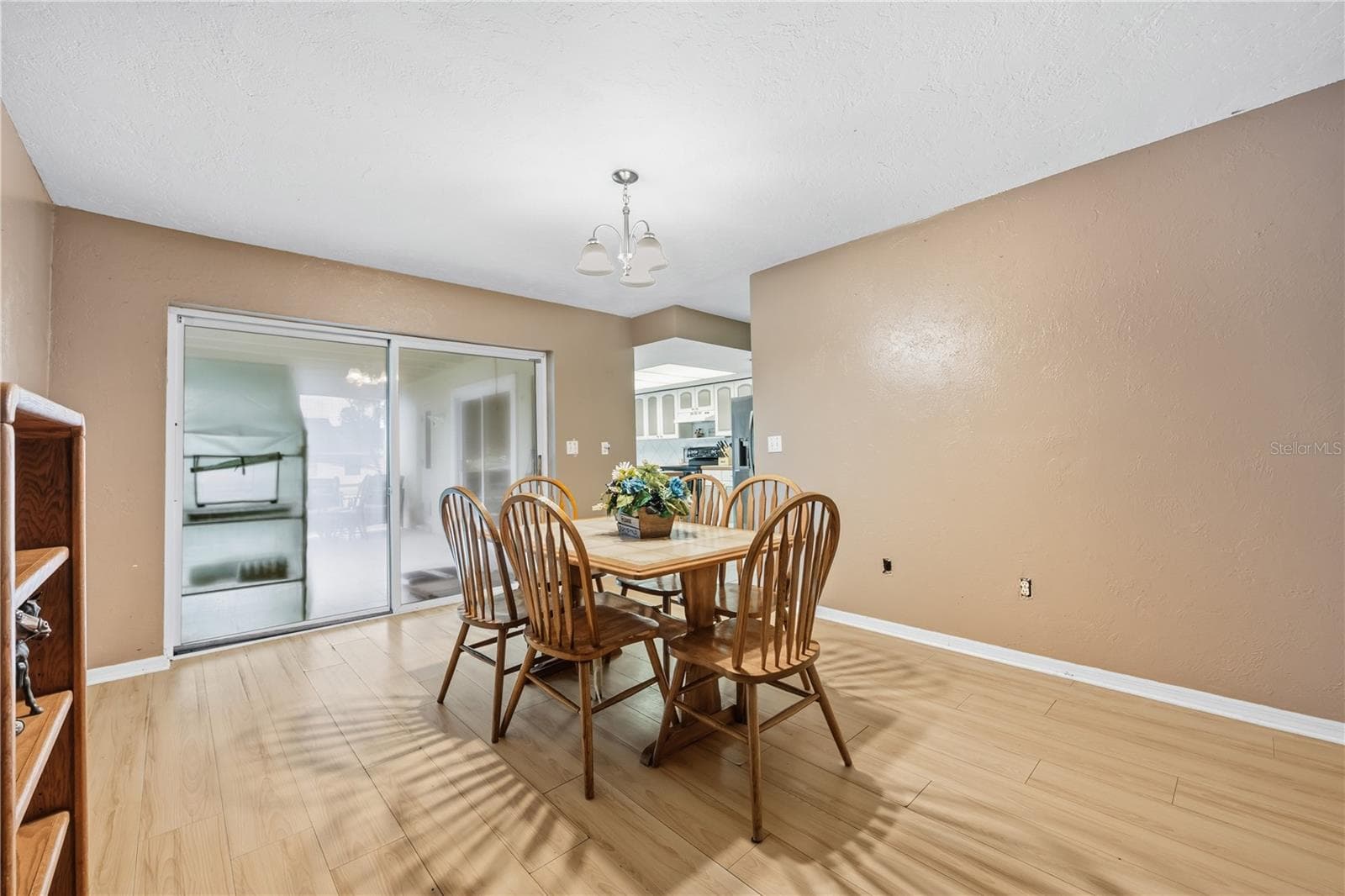 Additional angle of the dining space with views of the built-in shelving, main entryway, and easy access to both the kitchen and outdoor patio. - 3906 SANTIAGO ST, SEBRING