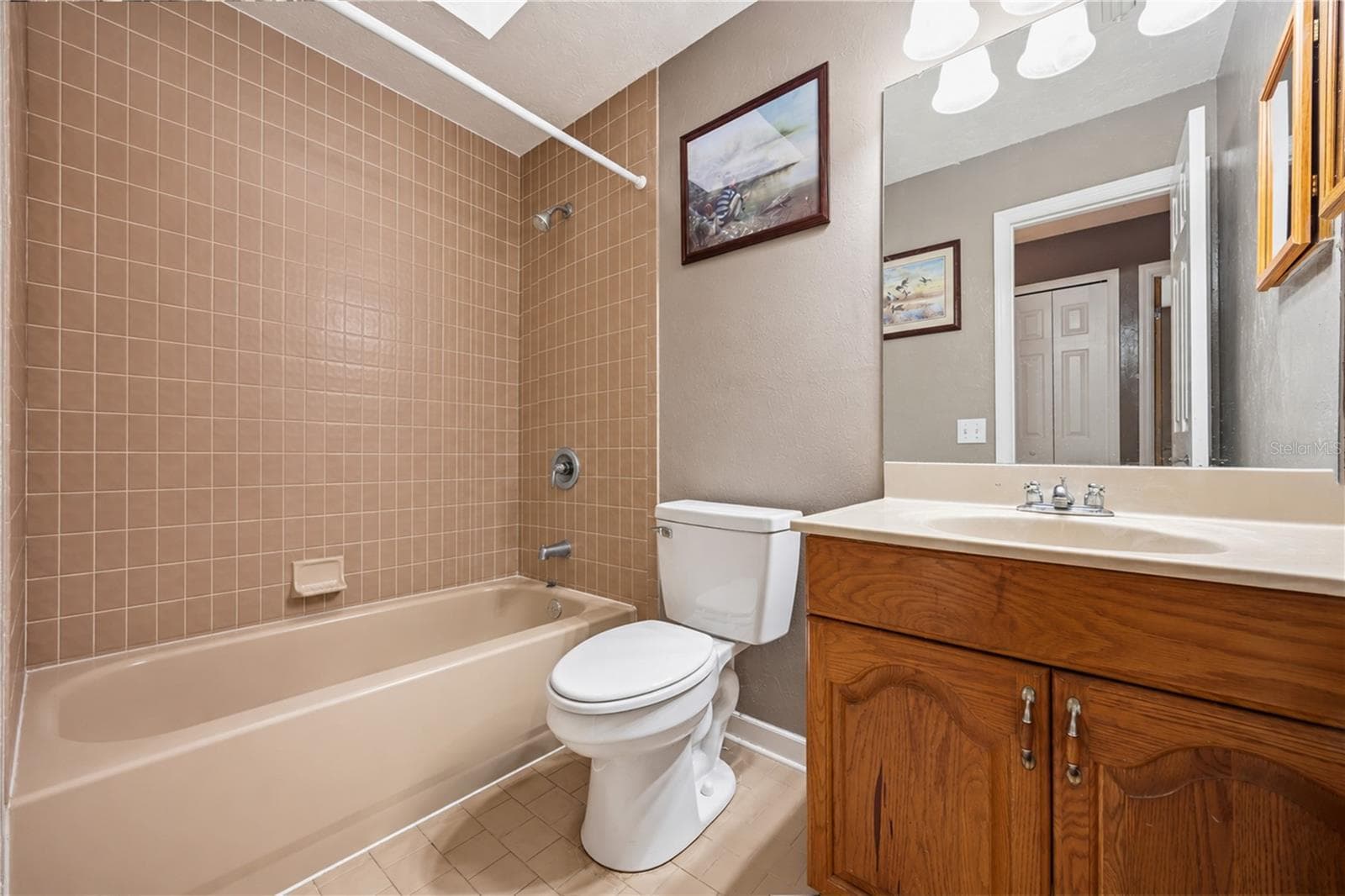 Full hall bathroom featuring a shower/tub combination, classic tile surround, and a traditional wood vanity with ample storage. - 3906 SANTIAGO ST, SEBRING