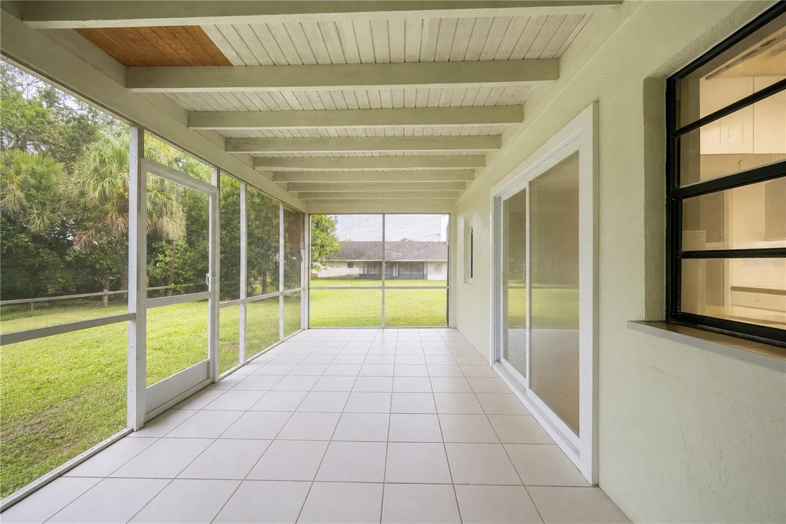 Fully screened-in tile lanai providing a peaceful, shaded outdoor living space overlooking the backyard. - 3906 SANTIAGO ST, SEBRING