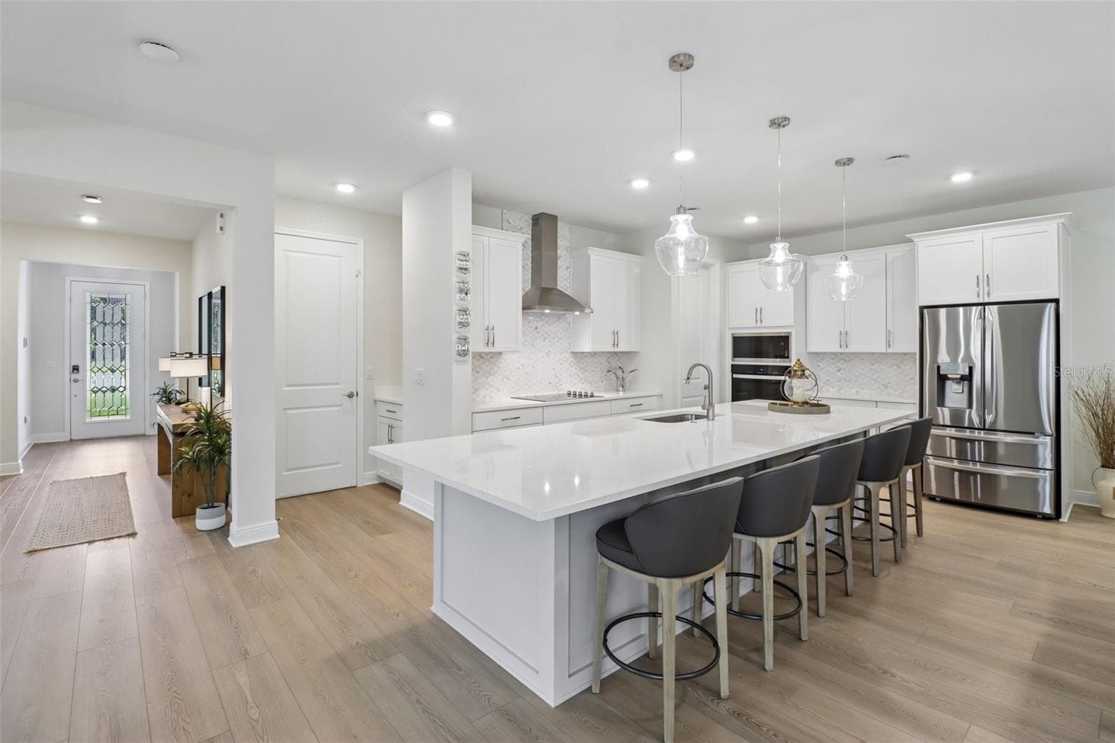 The OPEN-CONCEPT MAIN FLOOR centers around a must-see CHEF'S KITCHEN featuring sleek countertops, extensive cabinetry and storage, a decorative backsplash, pendant lighting, built-in STAINLESS STEEL APPLIANCES and a HUGE ISLAND with bar seating. - 2985 WATER CLOVER CT, APOPKA